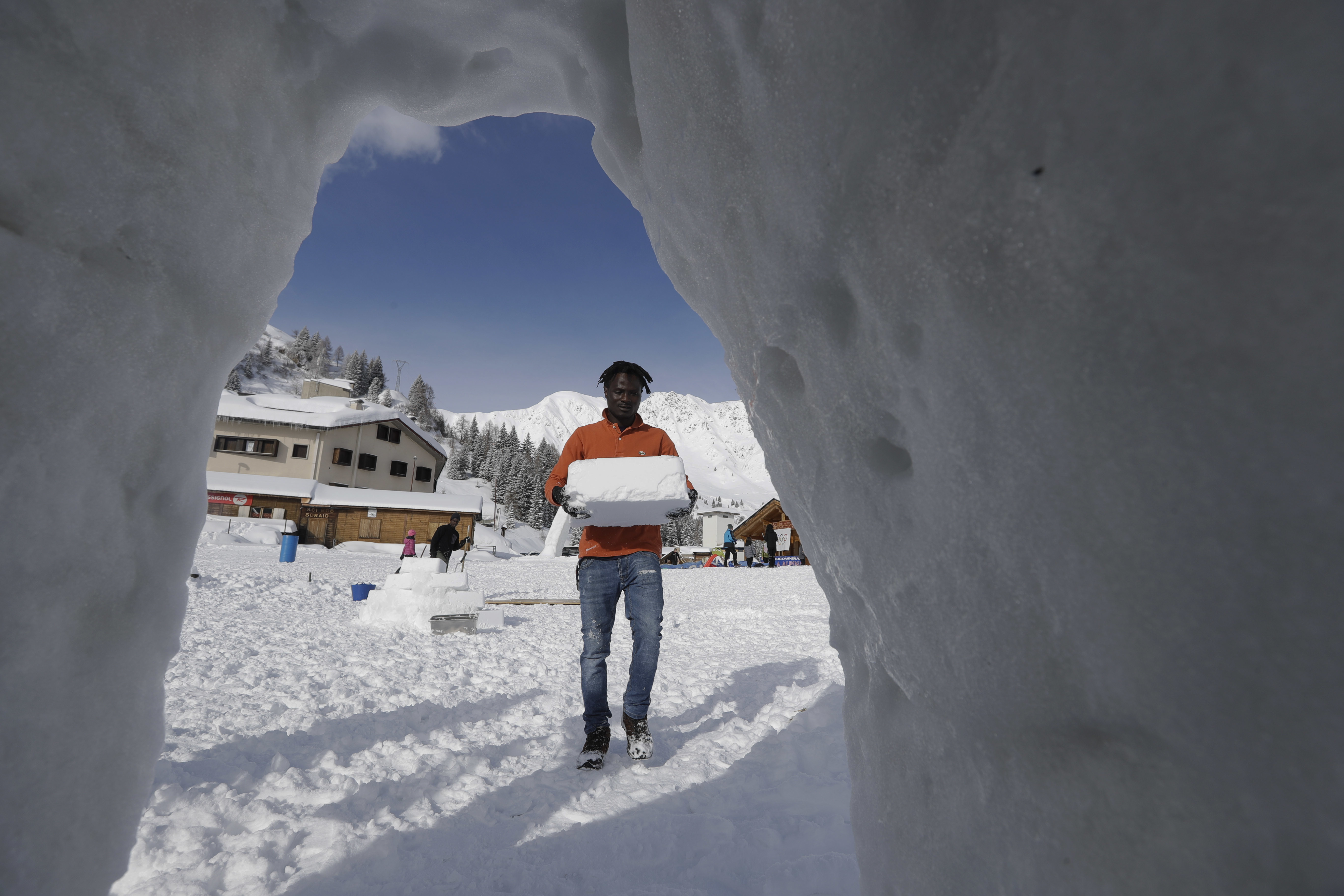 Omar Kanteh, of Gambia, carries a block of ice as he builds an igloo (Luca Bruno/AP)