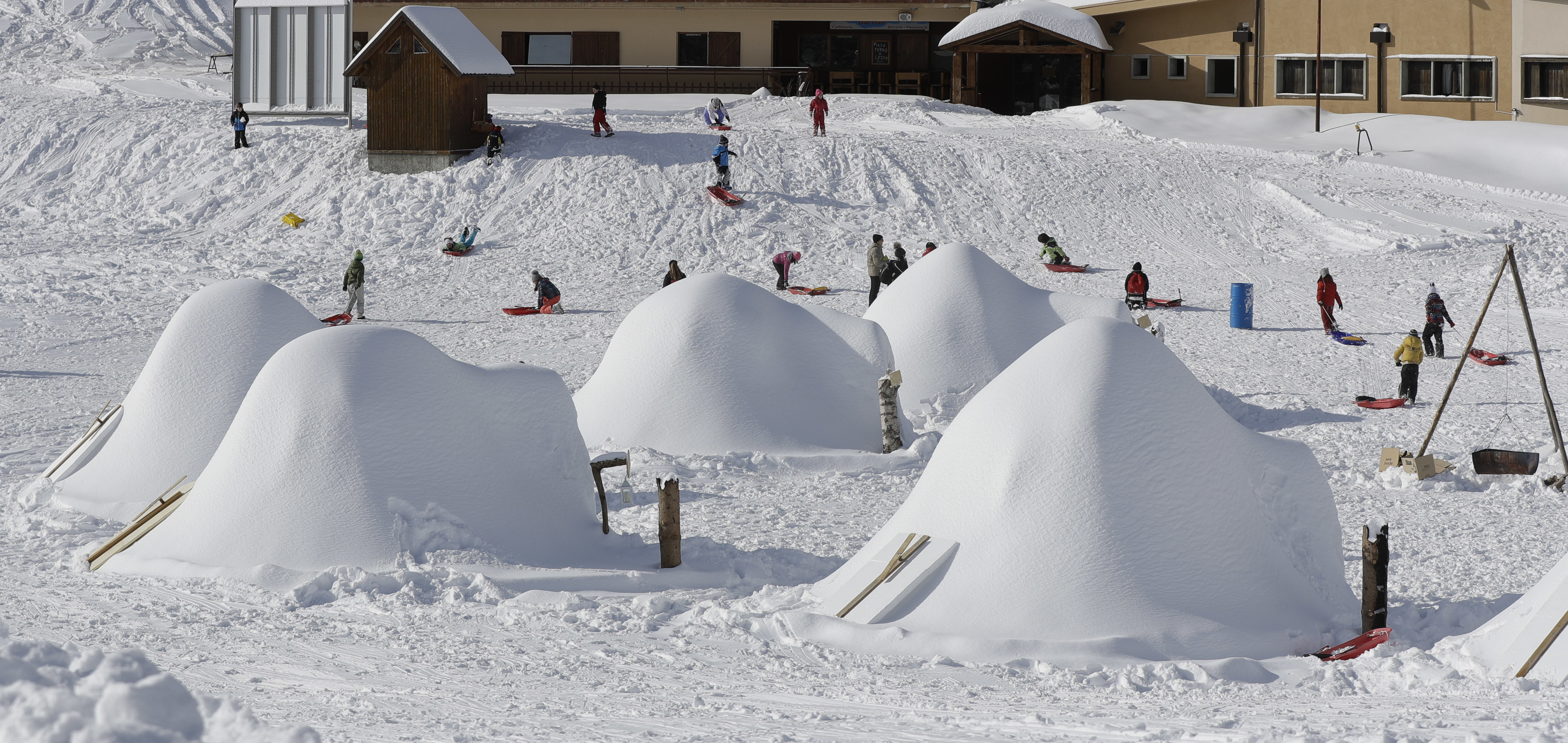 Children play with sledges behind an igloo village (Luca Bruno/AP)