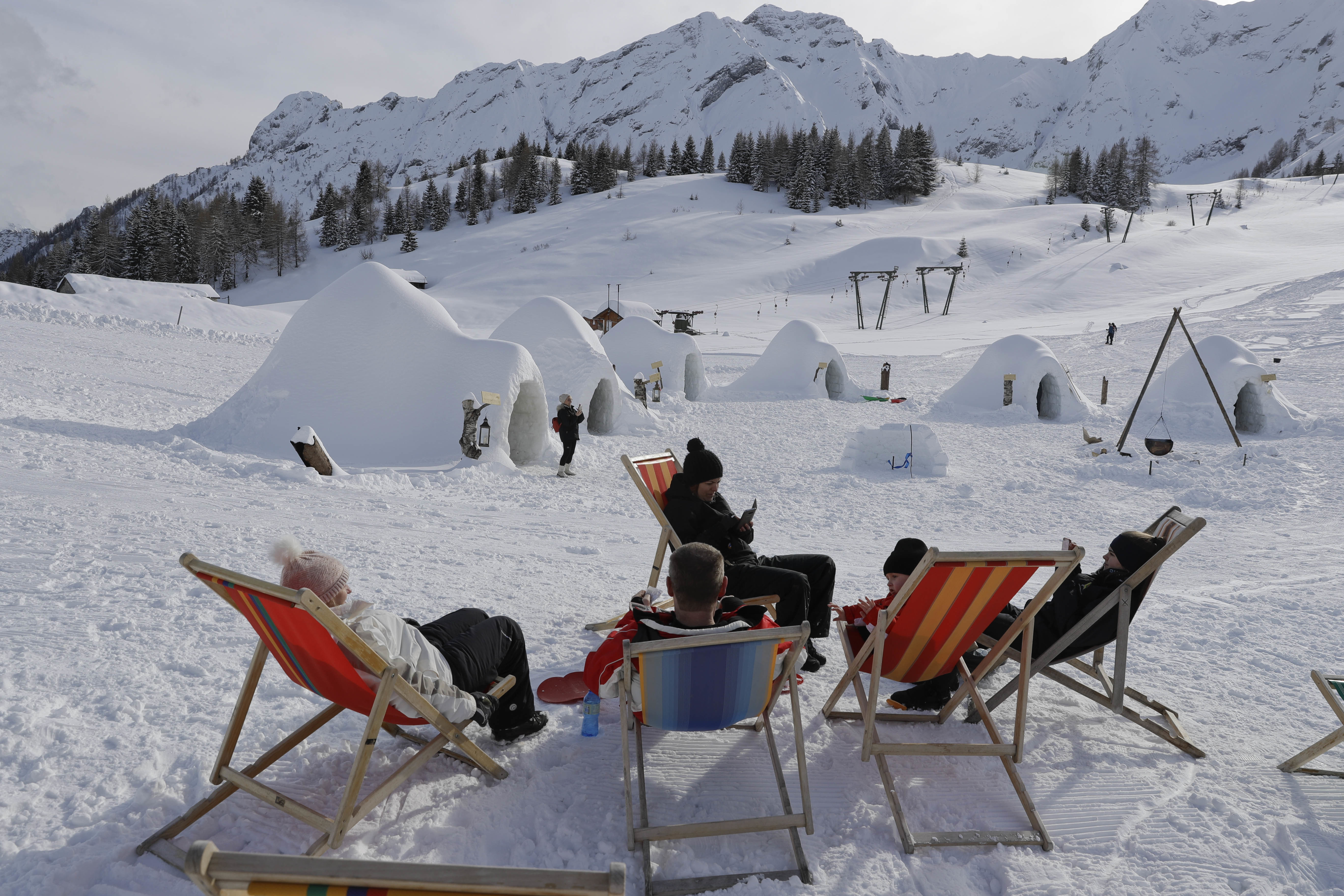 Tourists relax on deckchairs next to the igloo village (Luca Bruno/AP)