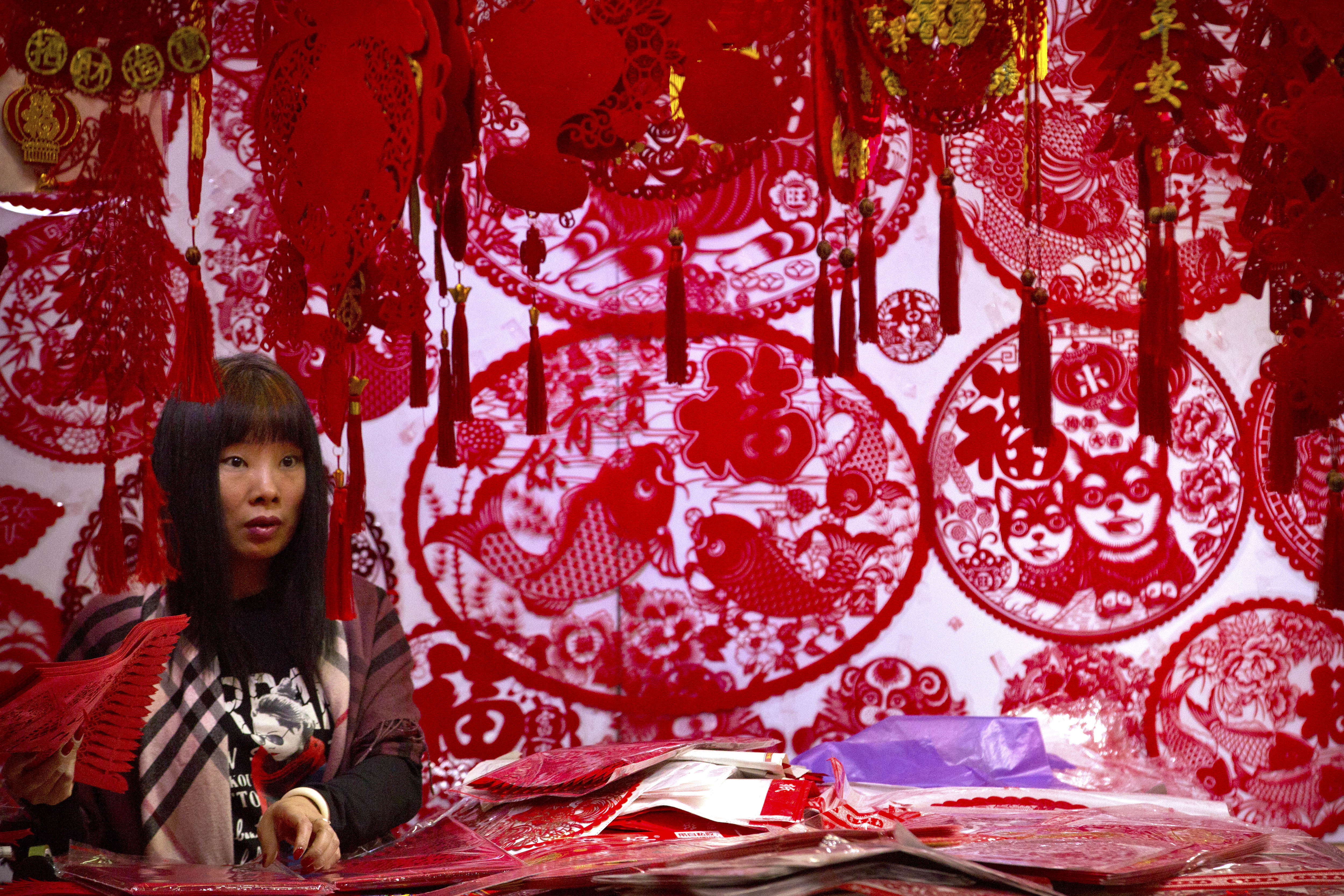 A vendor selling Lunar New Year decorations waits for customers (Mark Schiefelbein/AP)