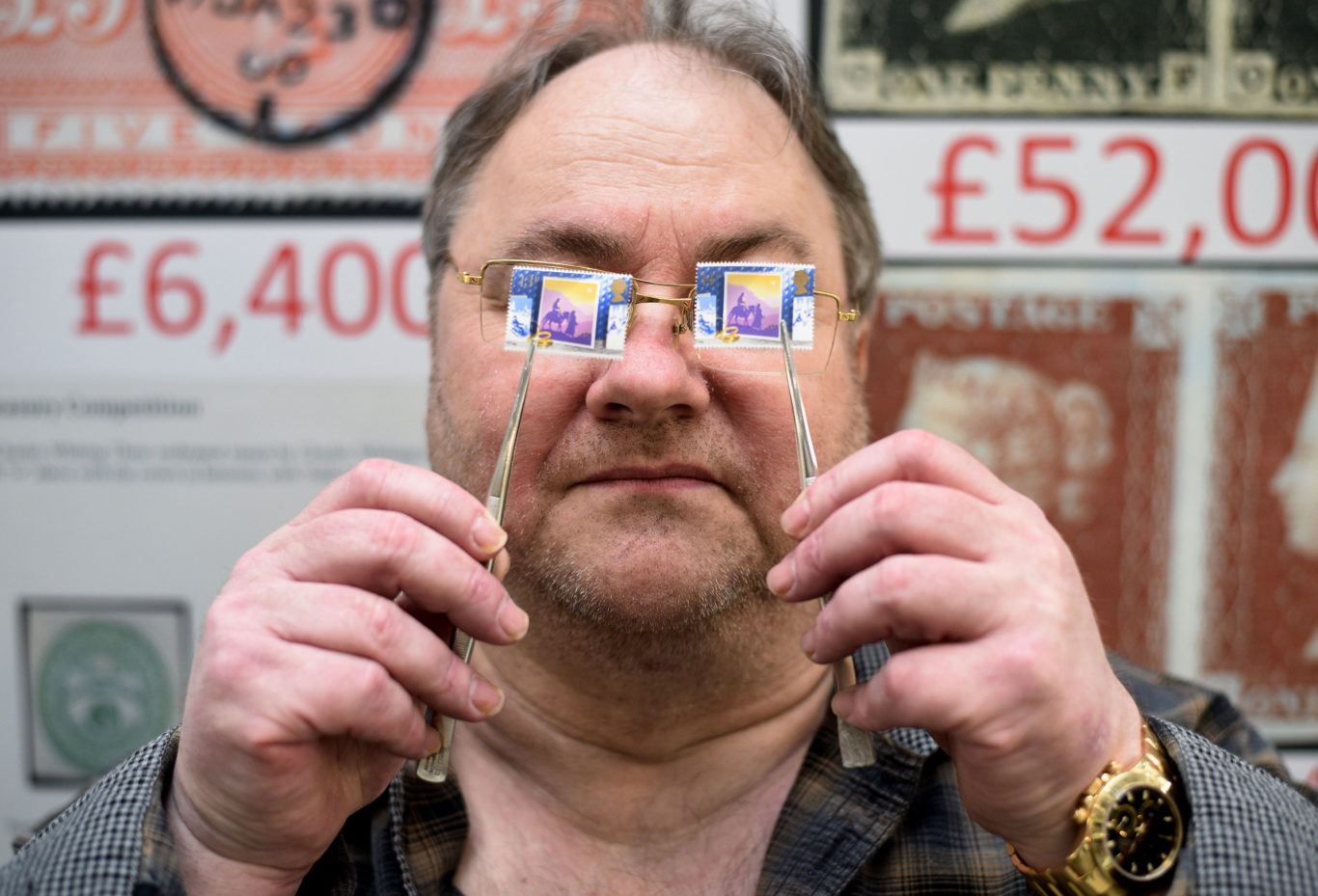 Stamp dealer Mark Bloxham holds up an SG1414a 1988 13p Christmas stamp (left) worth £8,000, next to a 14p version worth 14p (Kirsty O'Connor/PA)