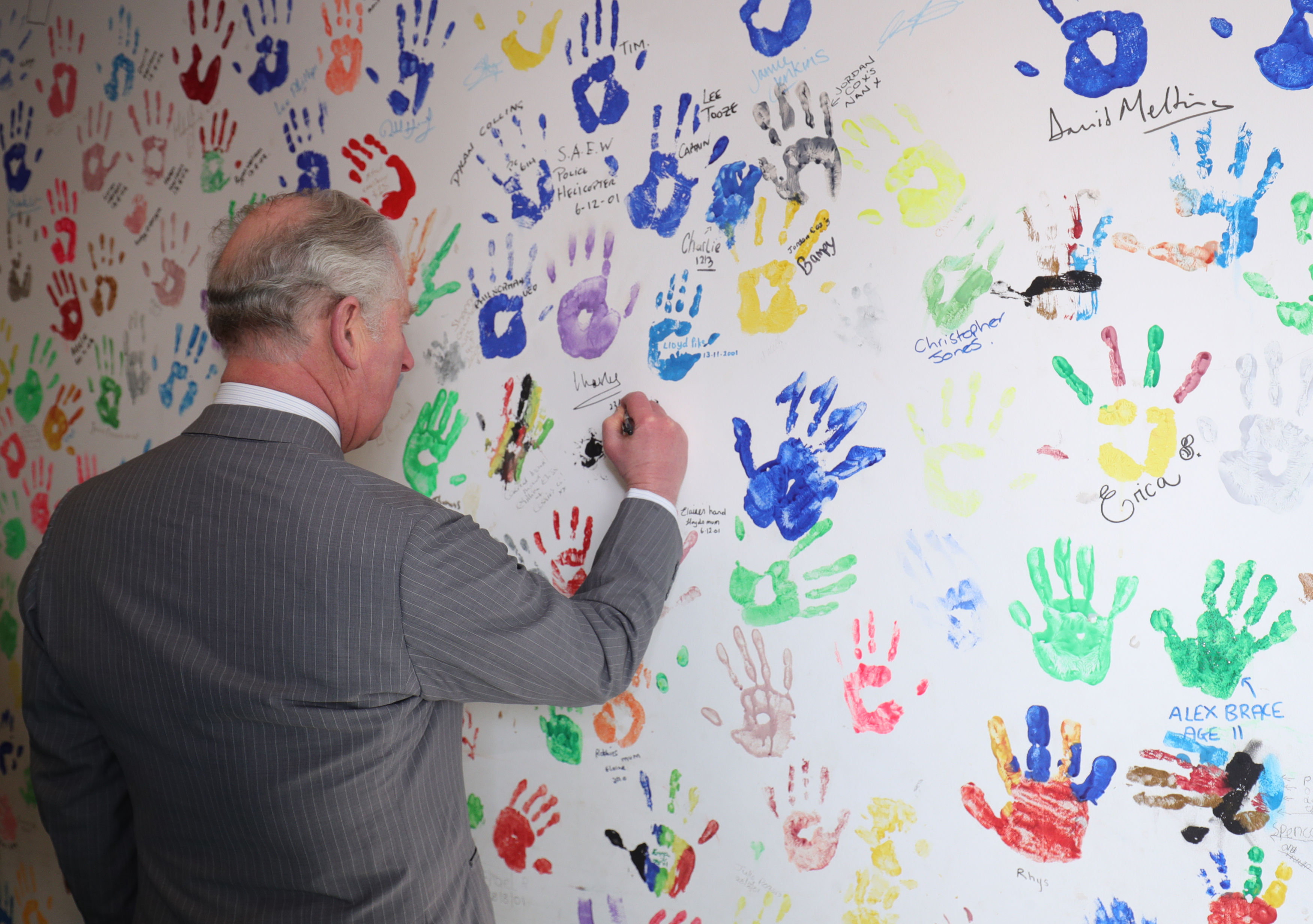 The Prince of Wales signs his handprint he created on a prior visit in 2001 (Aaron Chown/PA)