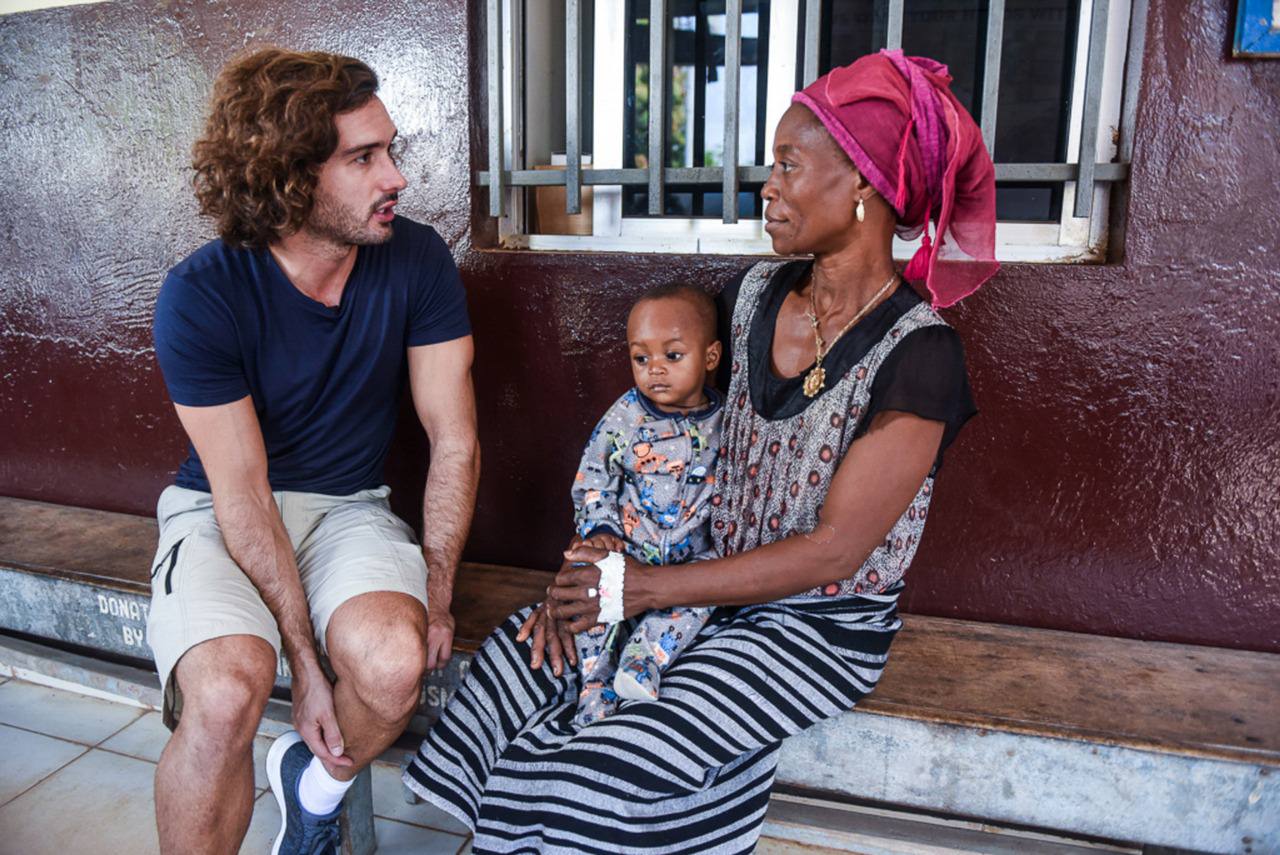 Joe Wicks speaking to a mother and child both suffering from malaria in Port Loko Community Health Centre (Sport Relief)