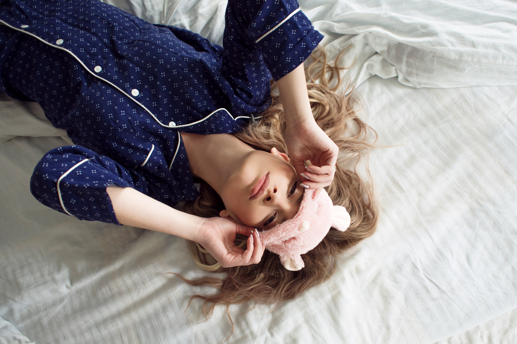  blonde girl in her bed in blue pajamas and sleep mask, top view