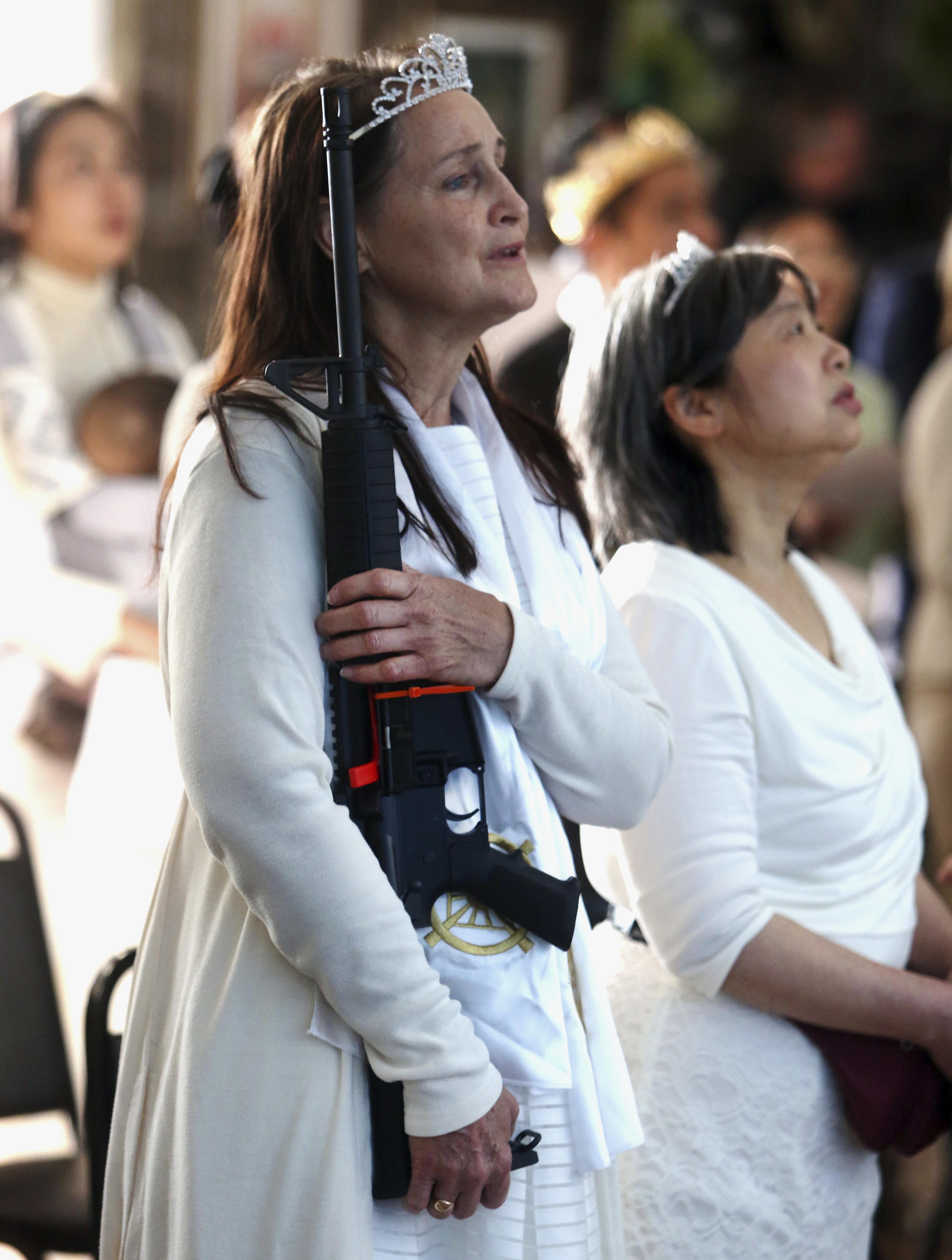 A woman sings the national anthem, while holding a weapon (Jacqueline Larma/AP)