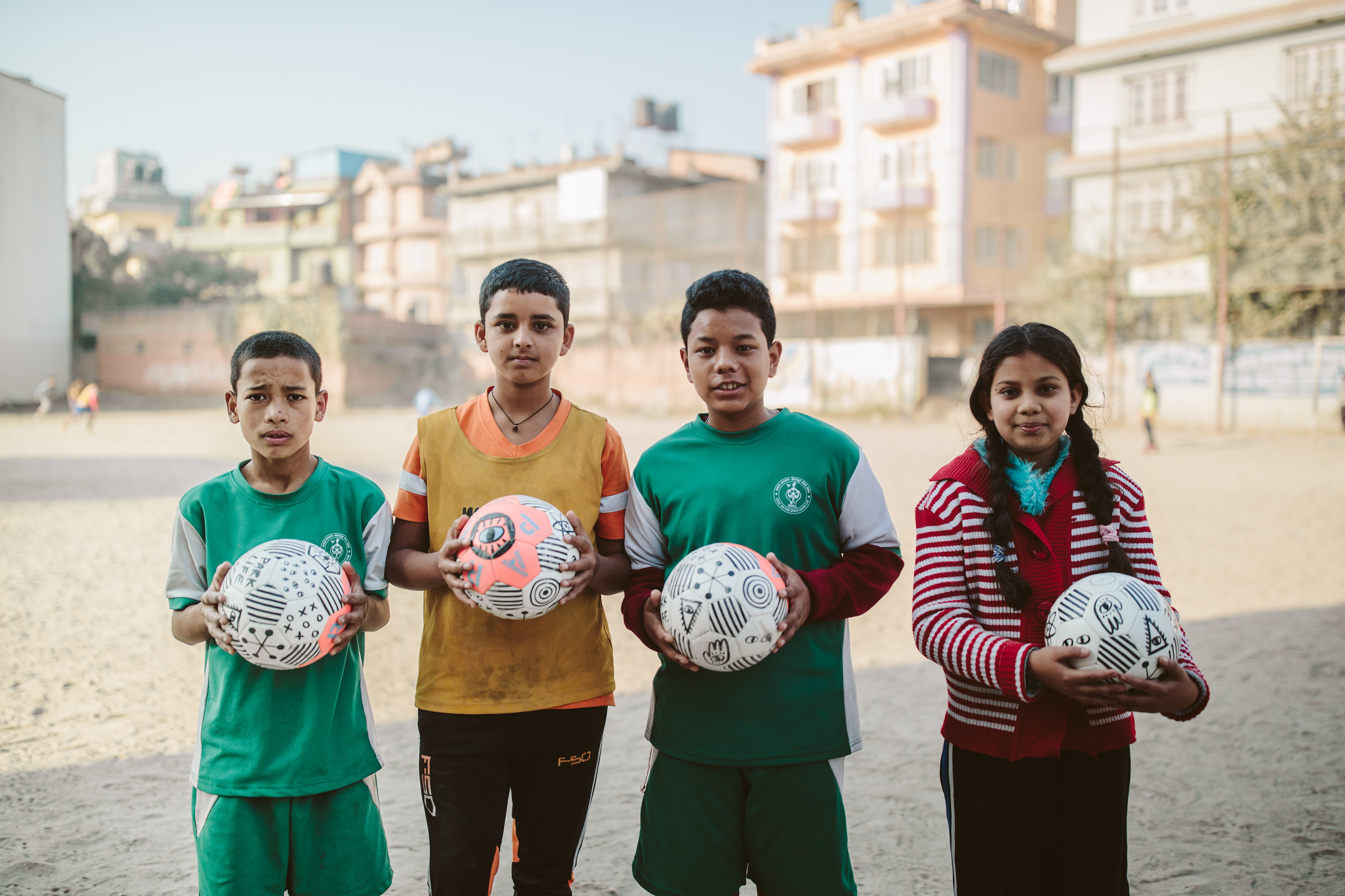 Children hold footballs donated by PARK Social Soccer Co