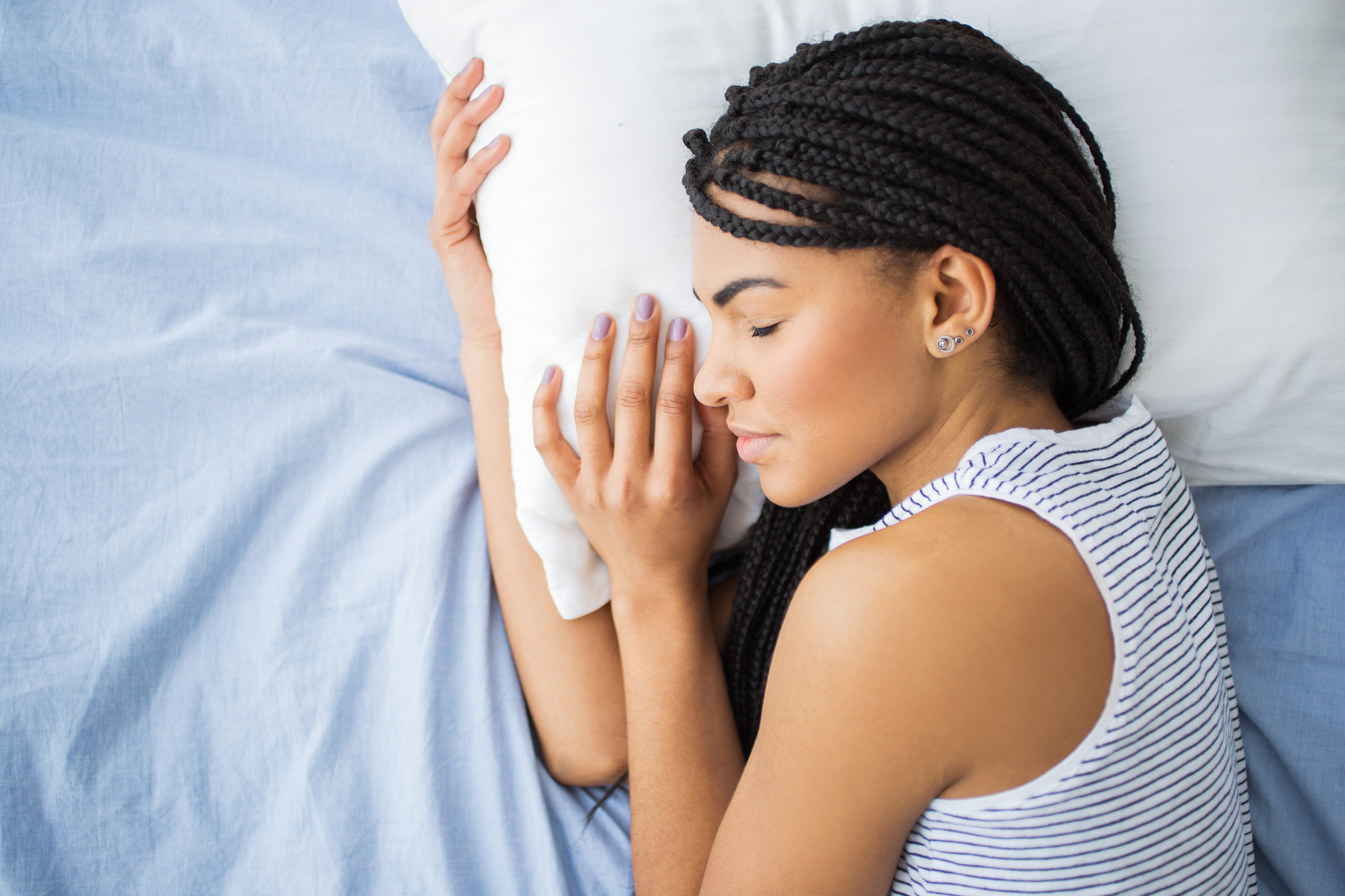 Portrait of African-American teenage girl wearing striped tank top sleeping in bed