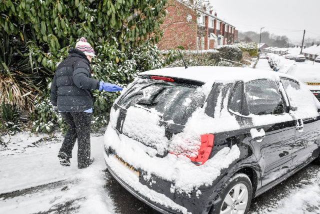 A woman cleans snow off a car in Bristol (Ben Birchall/PA)