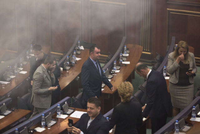 Politicians leave as smoke fills the auditorium (Visar Kryeziu/AP)