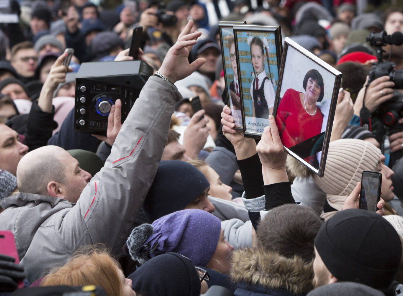 People hold portraits of relatives killed in a fire in Russia (Sergei Gavrilenko/AP)