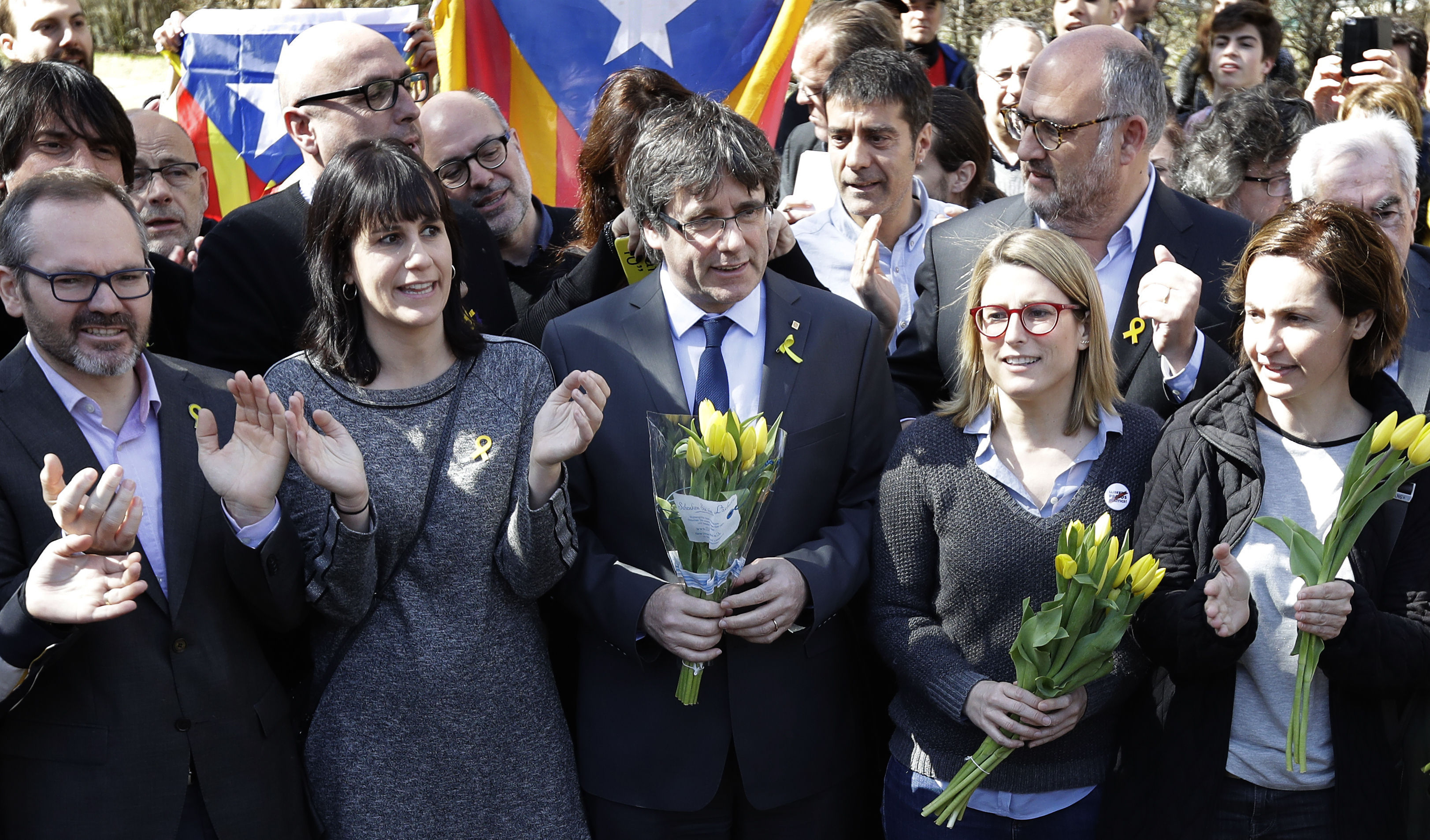 Carles Puigdemont holds a bunch of flowers as he and supporters sing after a news conference in Berlin (Michael Sohn/AP)