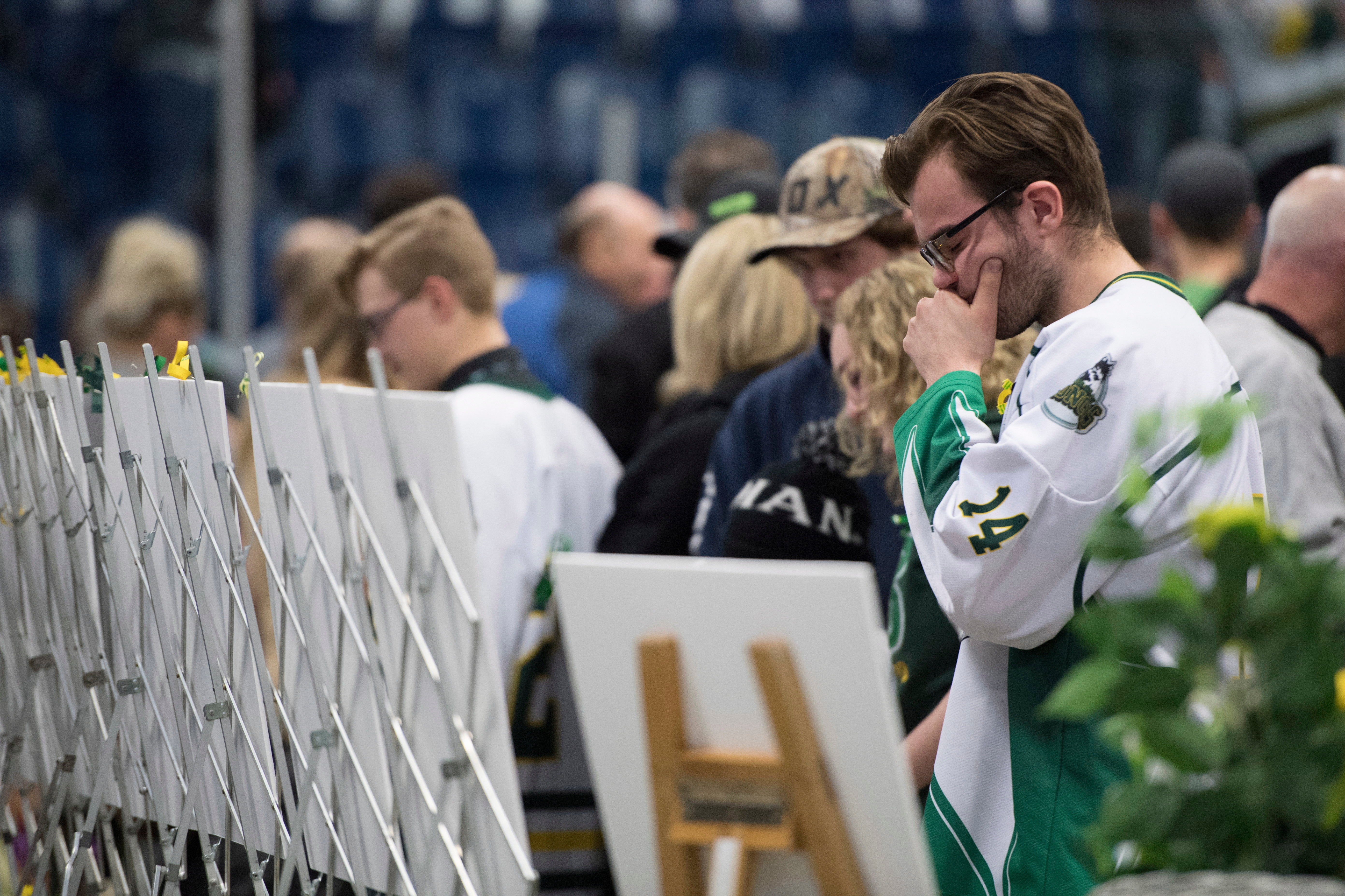 People look at photos of the victims during a vigil at the Elgar Petersen Arena (Jonathan Hayward/The Canadian Press via AP)