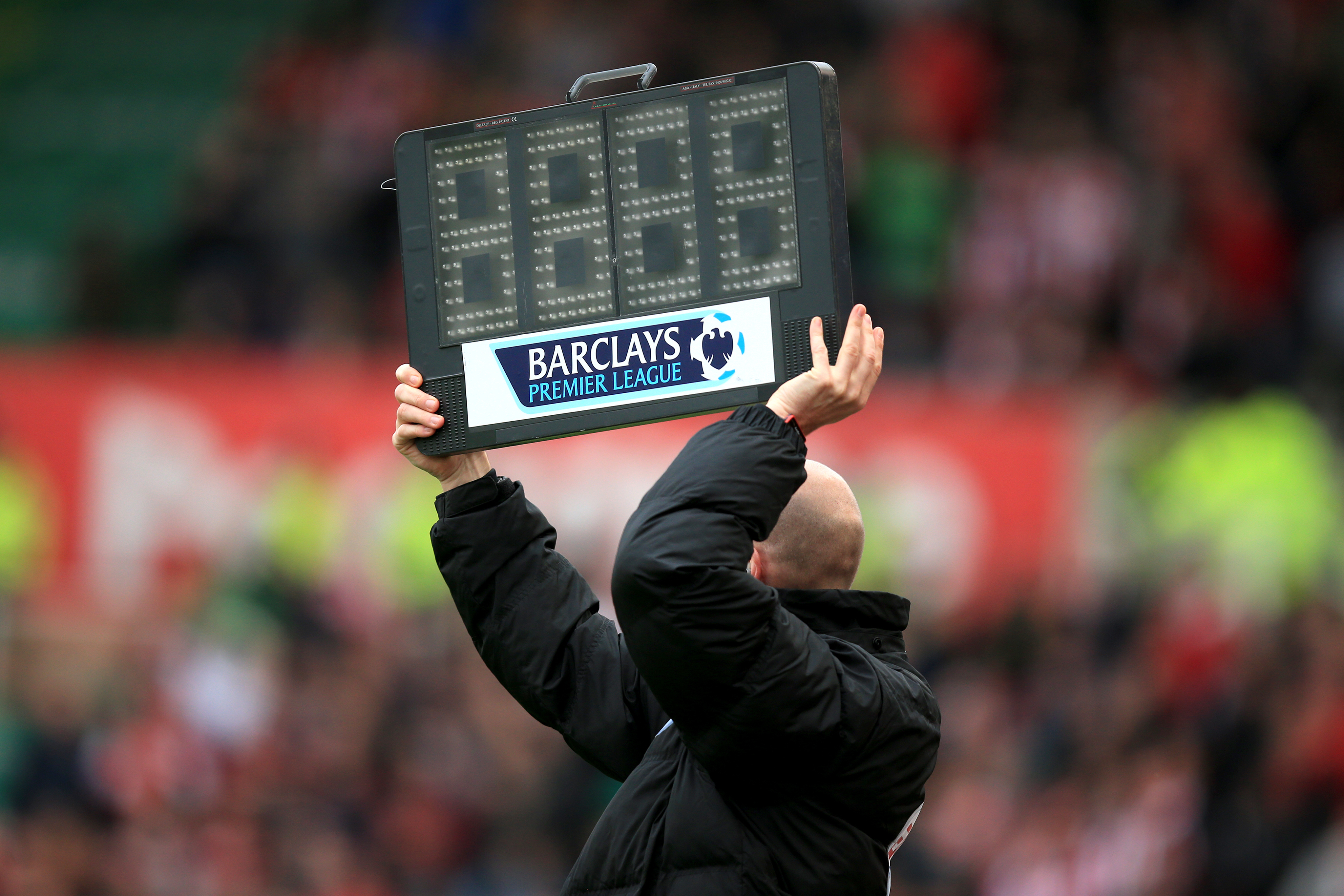 The fourth official holds up the board to signify added time