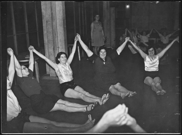 This image of an exercise class is accompanied with a description which says 'Peckham mothers can keep that schoolgirl figure' (Historic England Archive/PA)