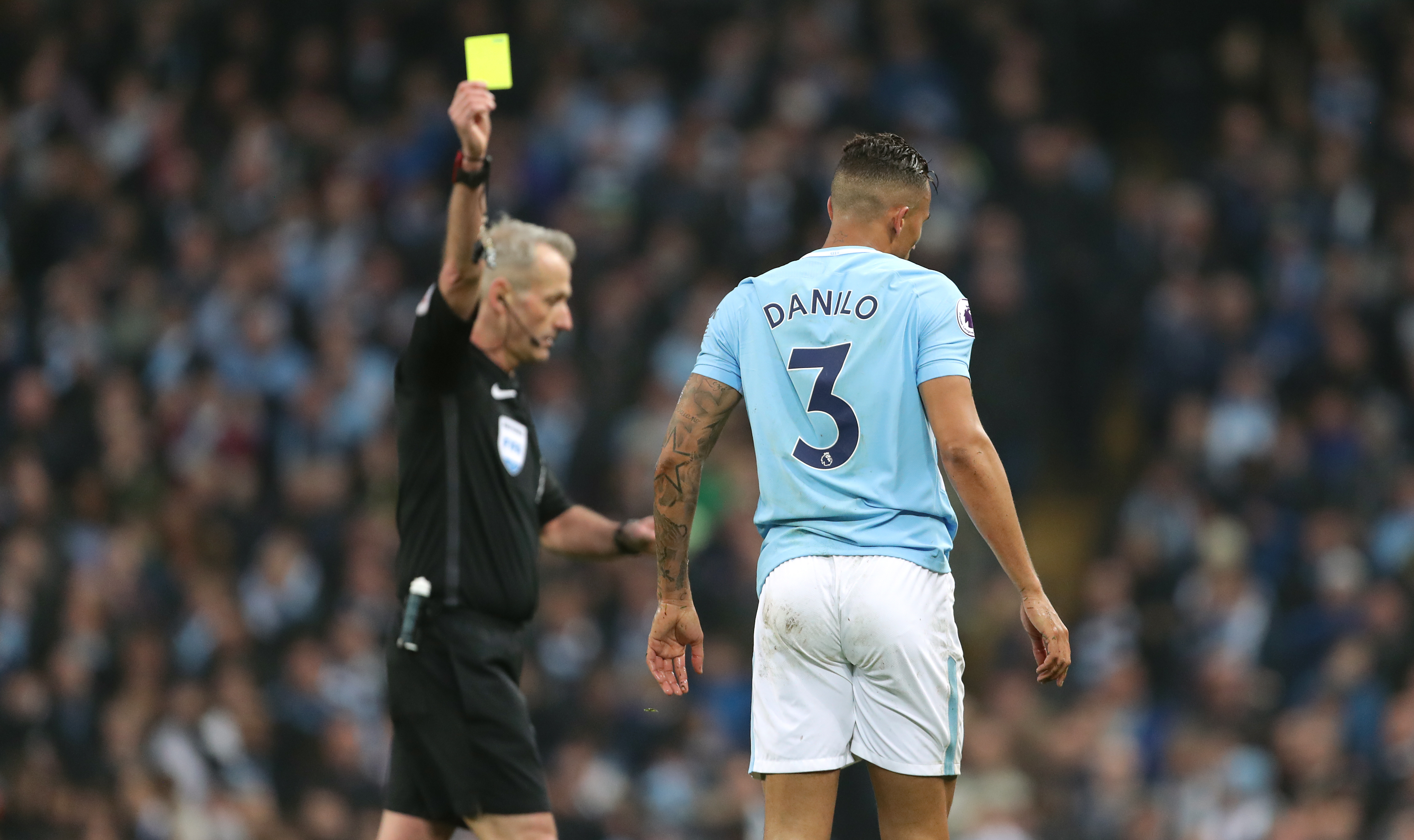 The referee shows a yellow card to Manchester City footballer Danilo