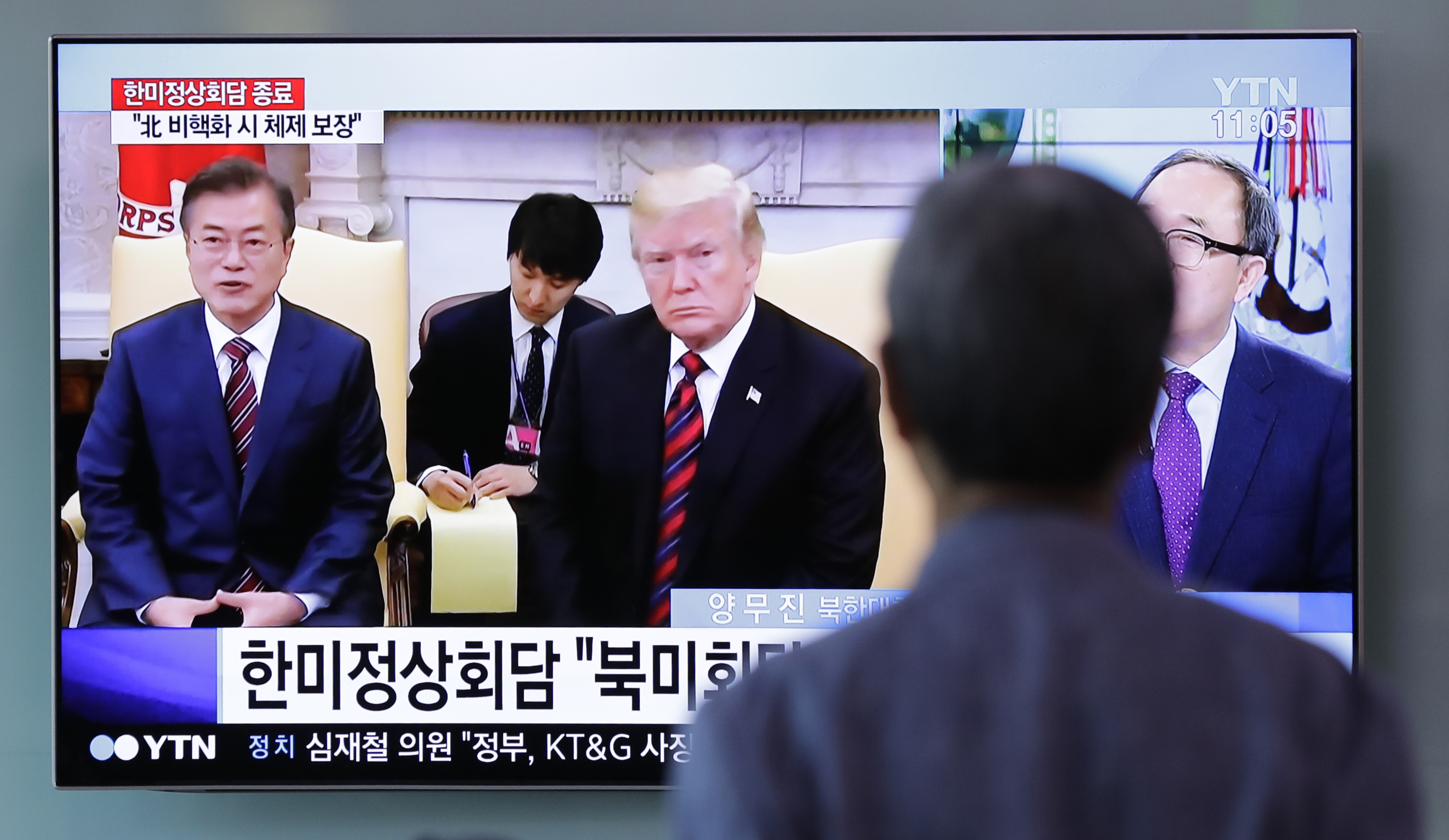 A man watches a TV screen showing footage of the summit meeting between US President Donald Trump and South Korean President Moon Jae-in (Lee Jin-man/AP)