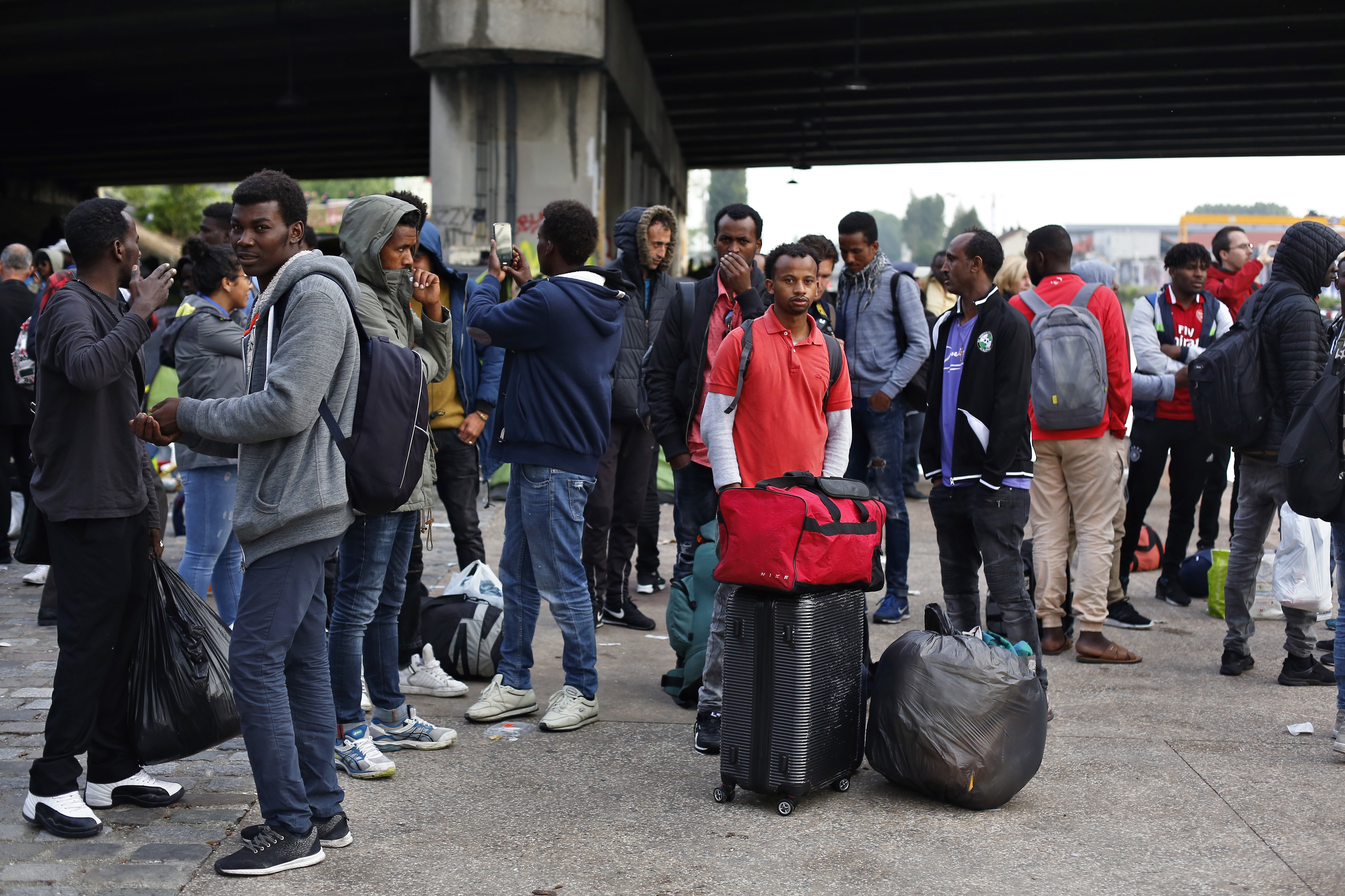 Migrants line up in a makeshift camp during its evacuation in Paris 
