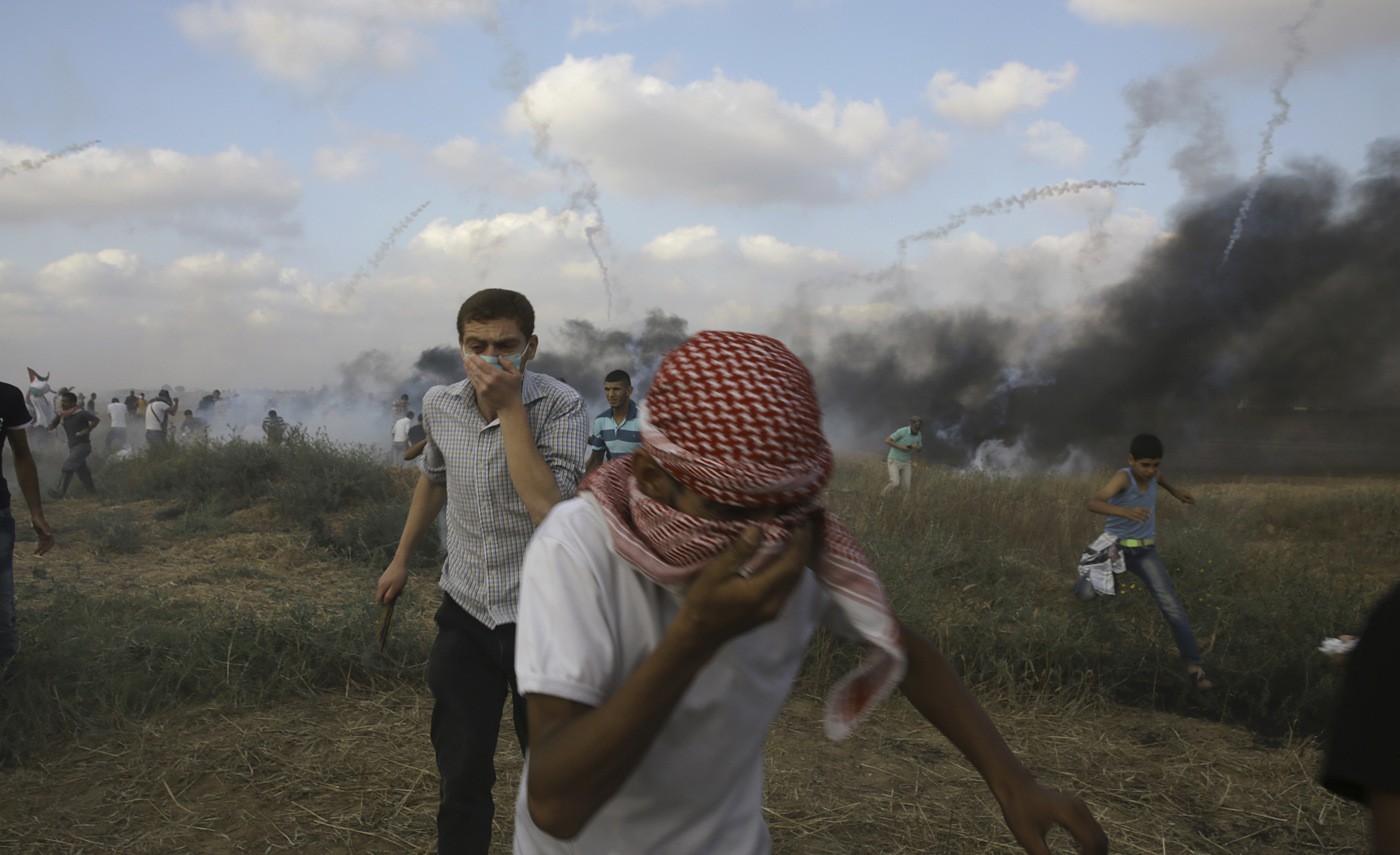 Palestinian protesters take cover from teargas fired by Israeli troops
