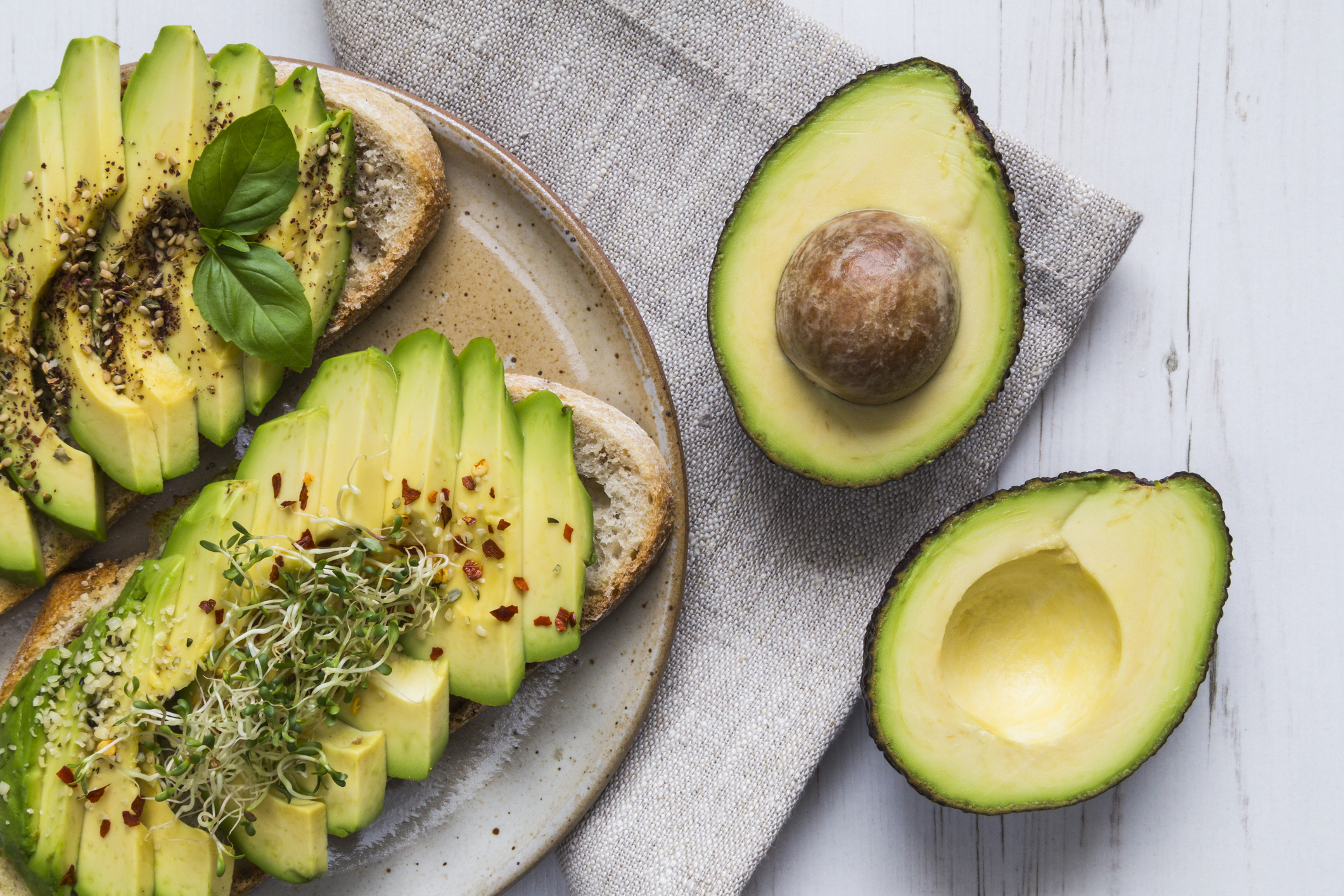 Toast with sliced avocado topping, basil leaf and seasoning.