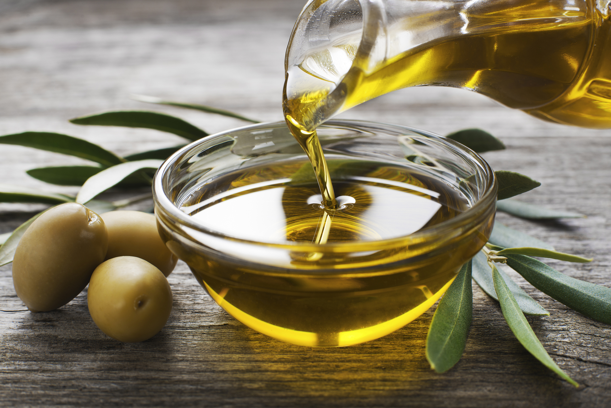 Bottle pouring virgin olive oil in a bowl close up