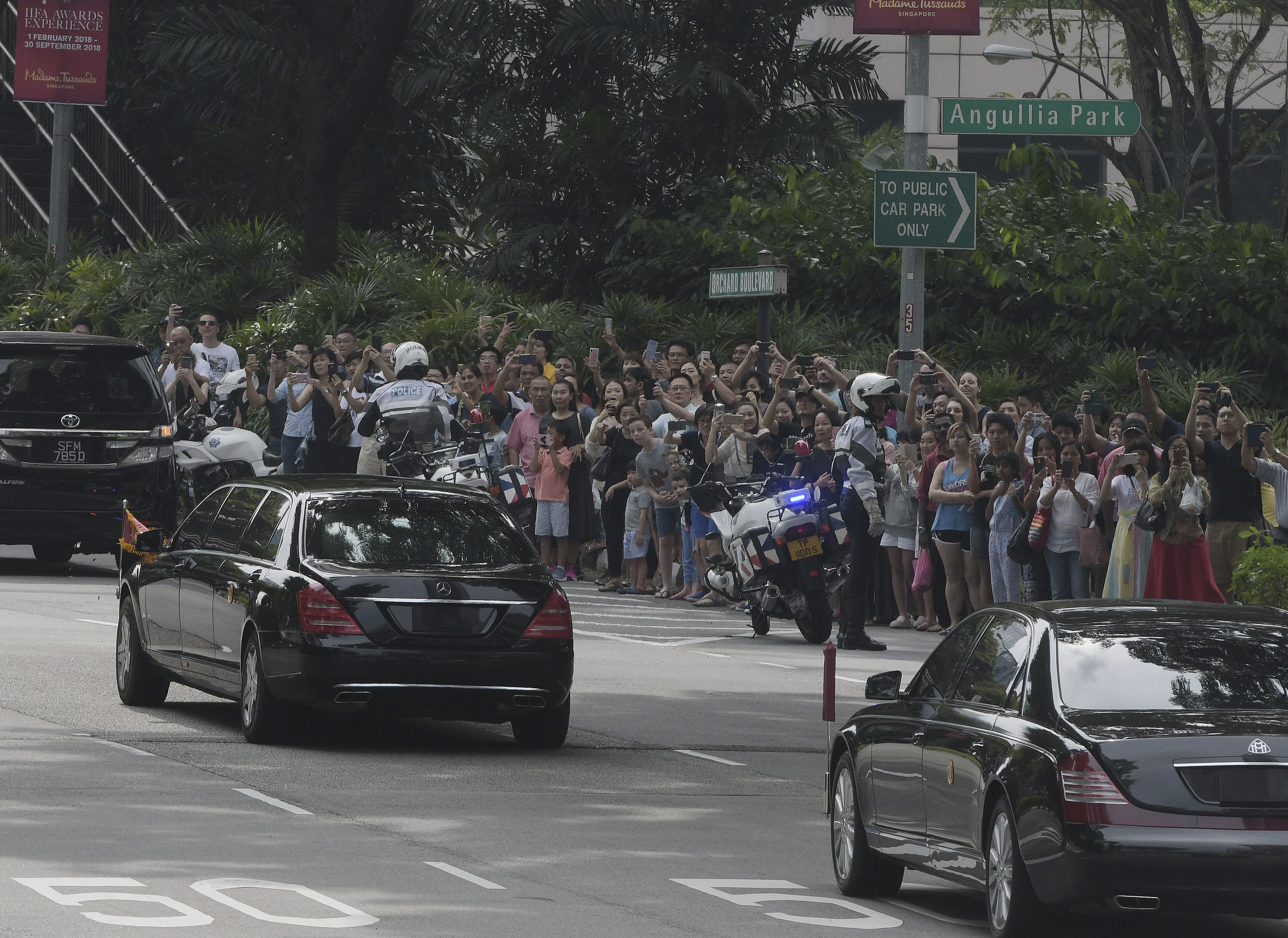 Crowds watch the North Korean motorcade in Singapore