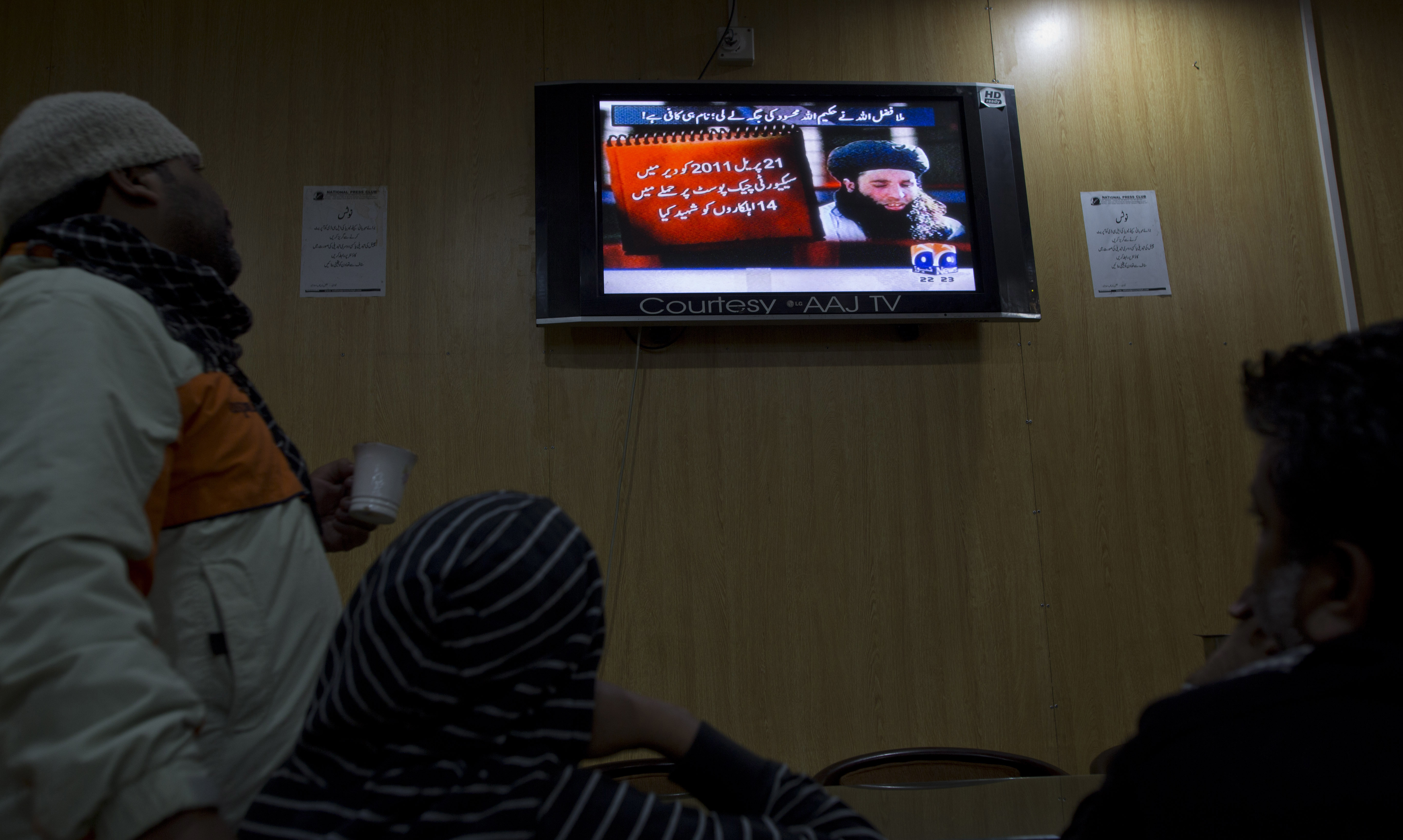 People watch a 2013 news report about the newly selected leader of the Pakistani Taliban leader Mullah Fazlullah