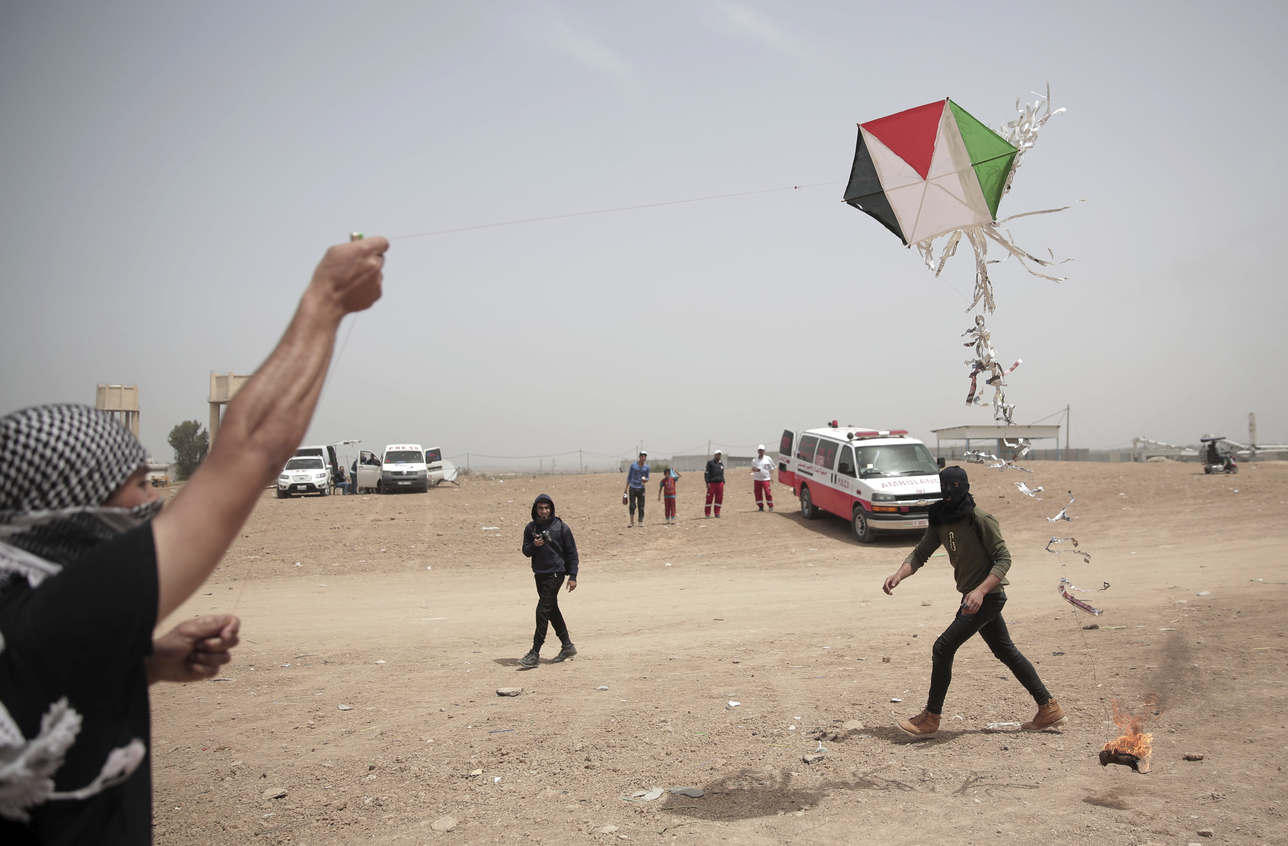 Palestinian protesters fly a kite with a burning rag dangling from its tail 