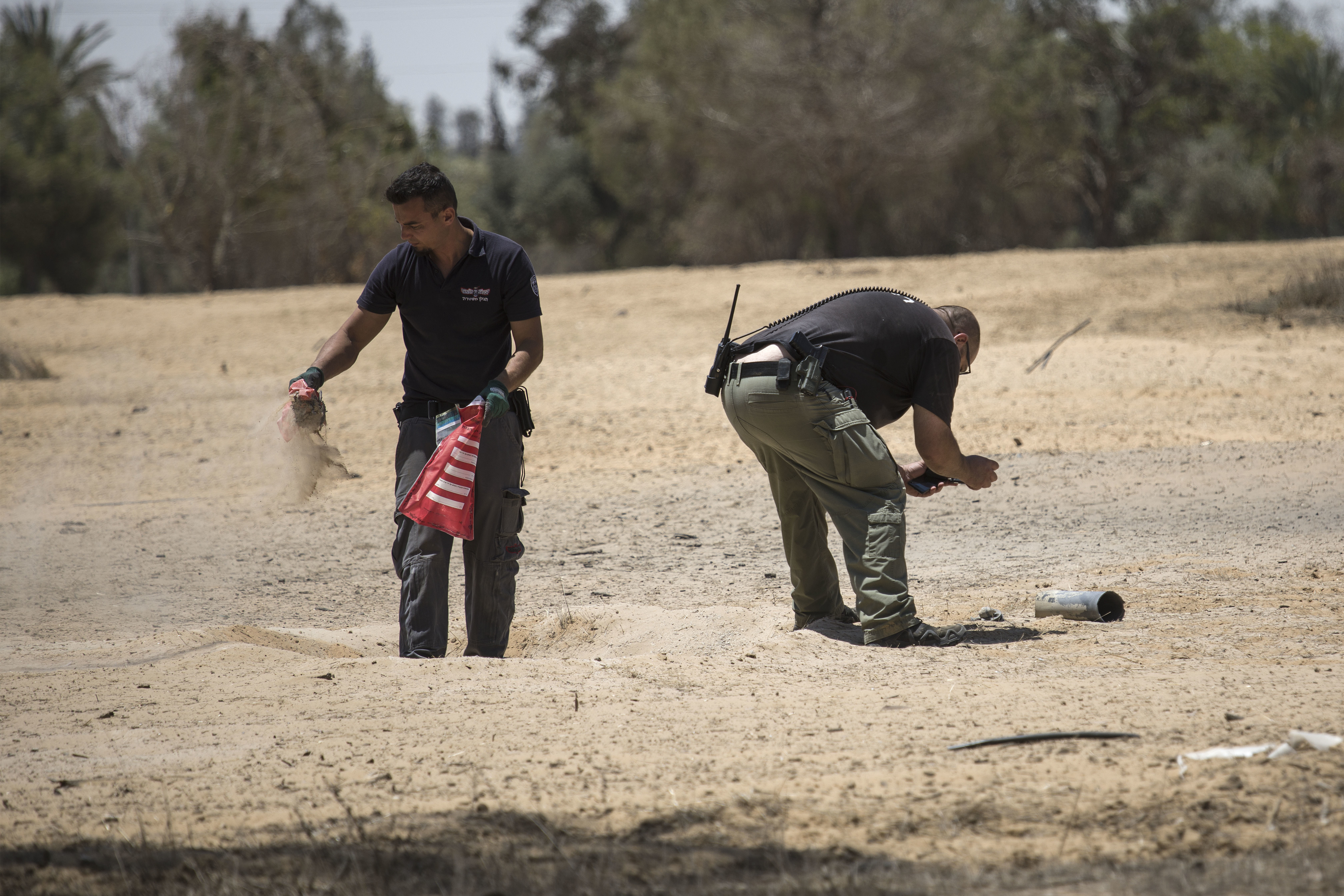 An Israeli police sapper and security man inspect a missile launched from the Gaza Strip