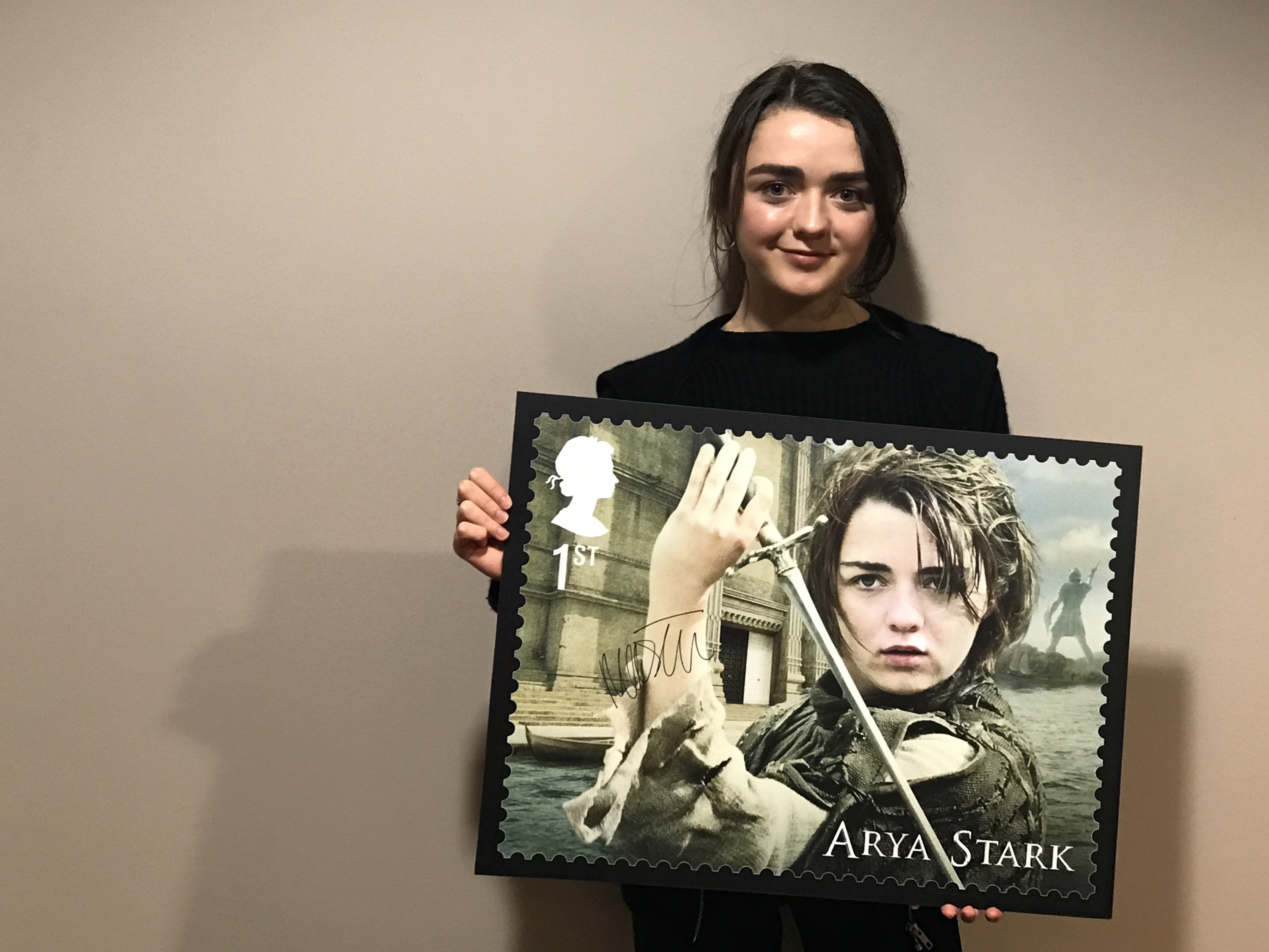 Maisie Williams holding up her enlarged stamp