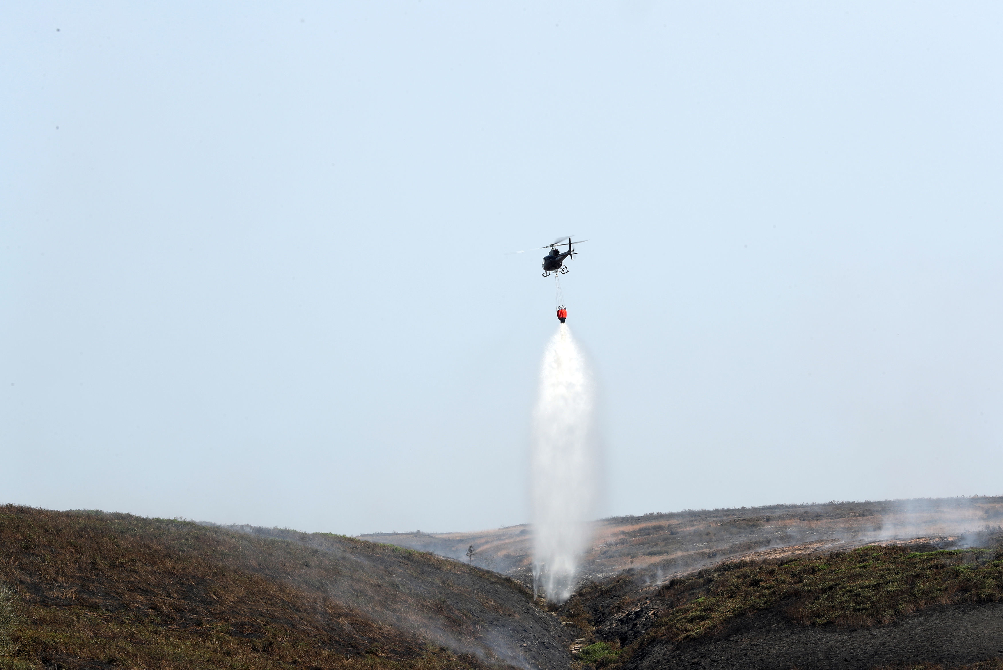 A helicopter drops water as firefighters tackle a wildfire on Saddleworth Moor