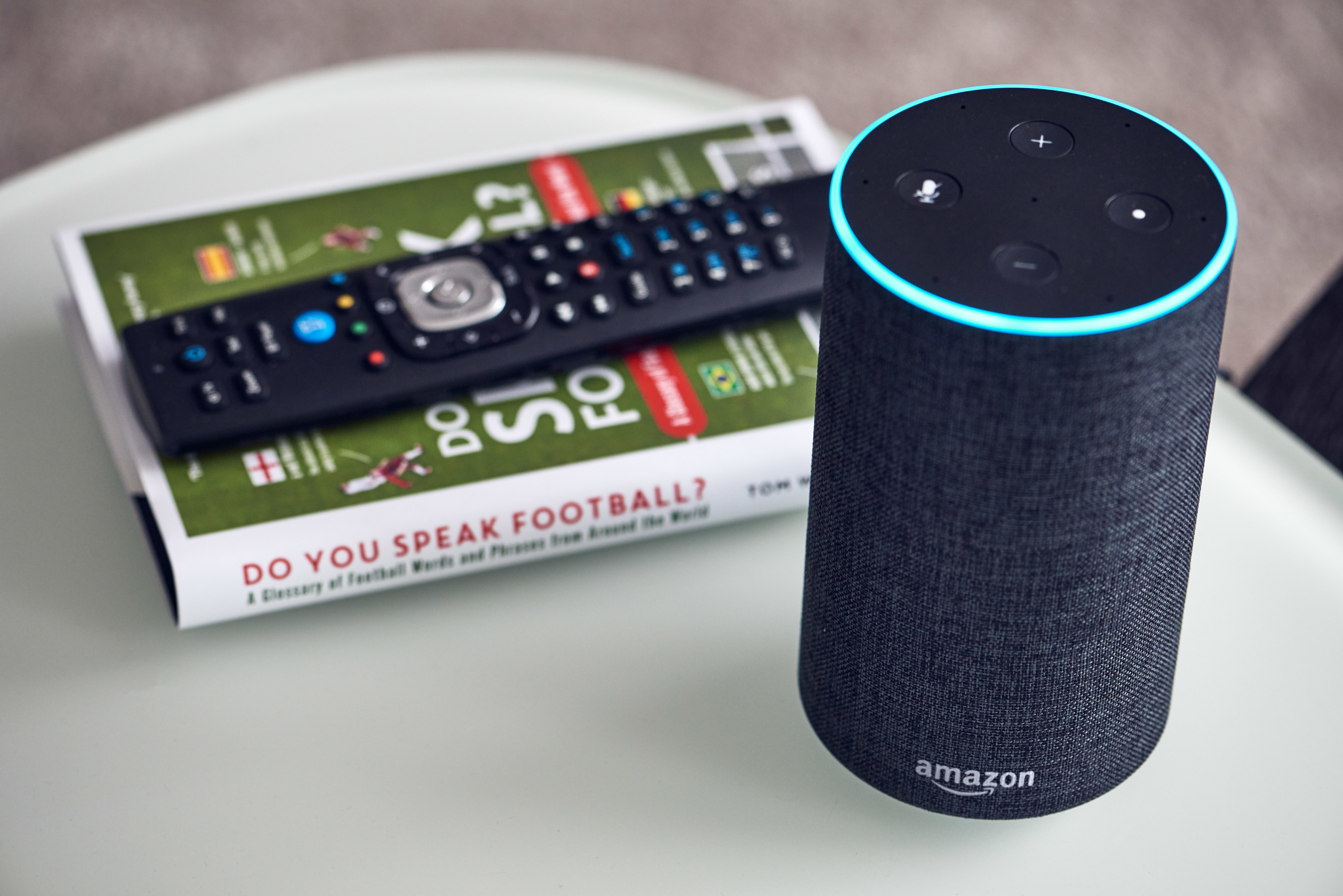 An Amazon Echo next to a book about football