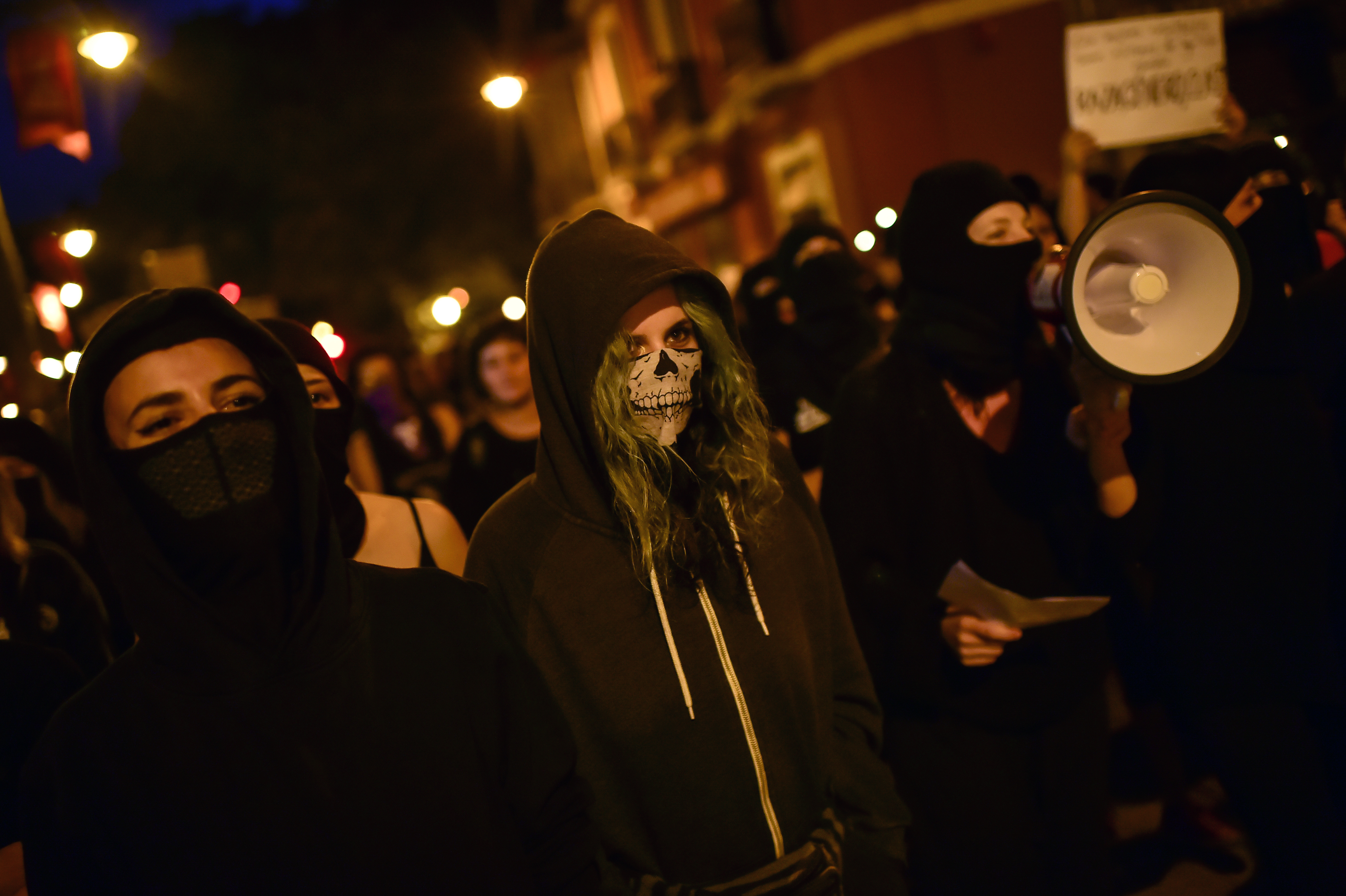 Women activists hold candles with their faces covered, while taking part in a protest against male violence, before the famous San Fermin festival in Pamplona