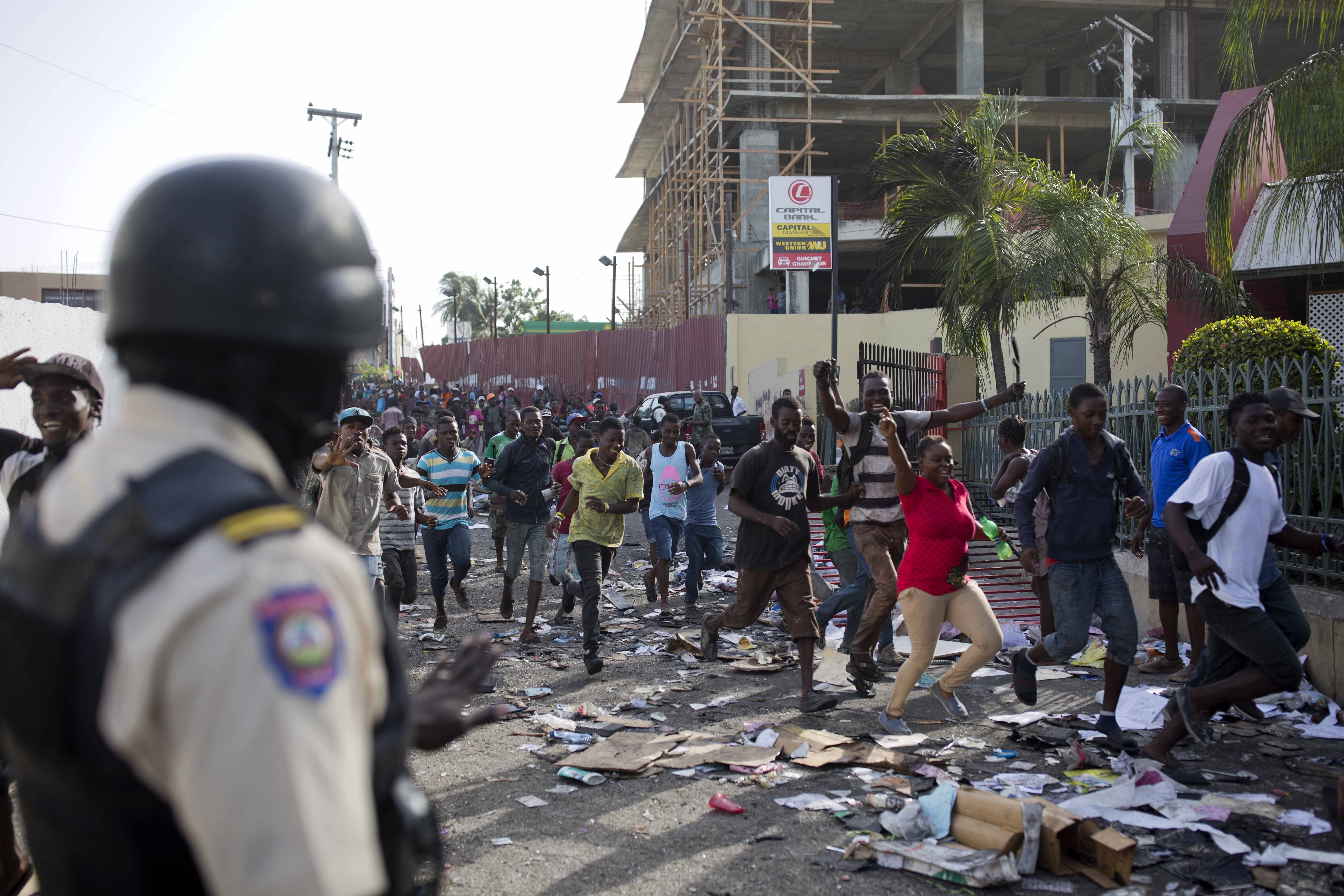 A crowd enters the Delimart supermarket complex, which had been burned during two days of protests in Port-au-Prince
