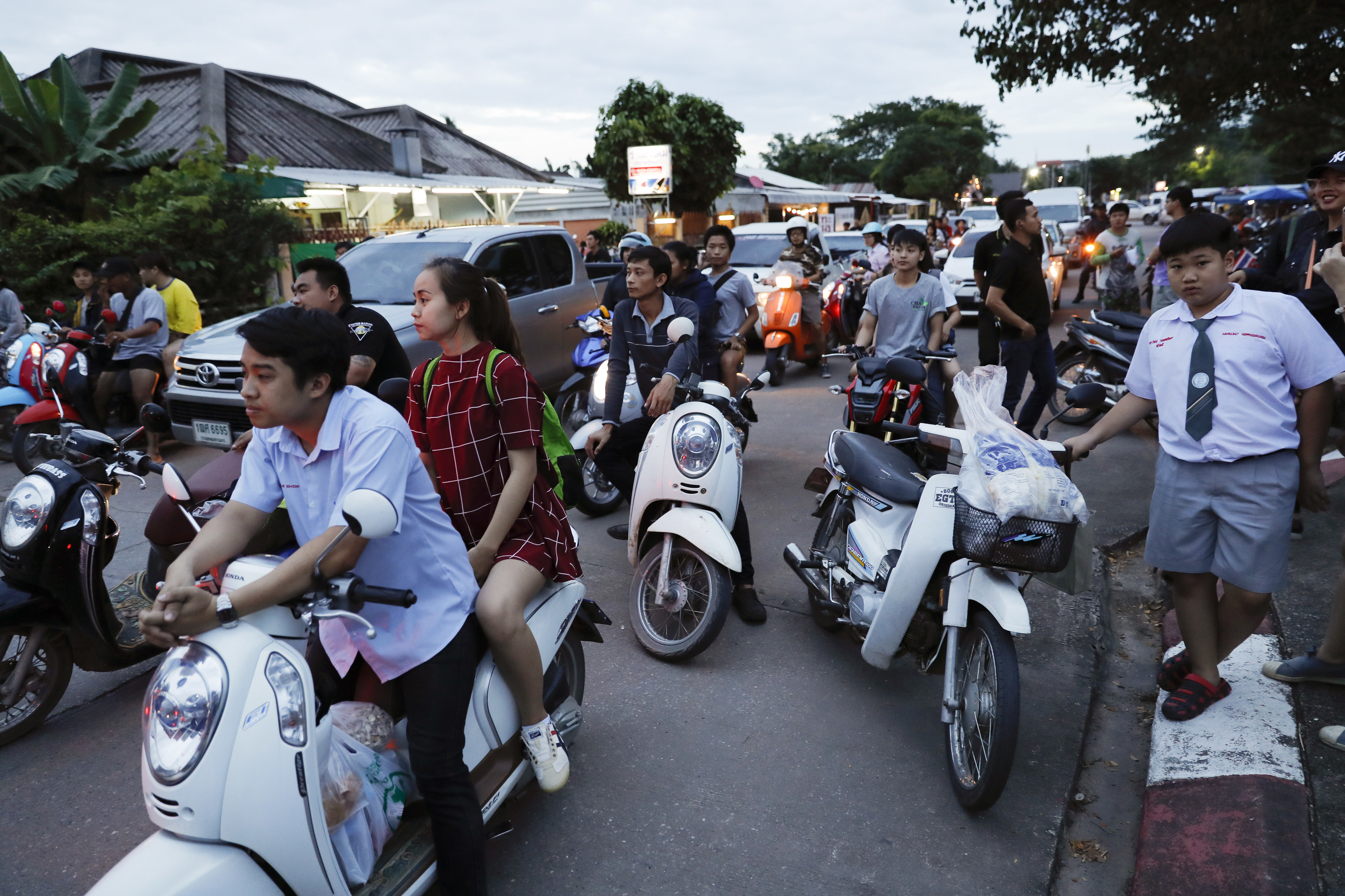 People wait as police block the road during an emergency helicopter evacuation in Chiang Rai