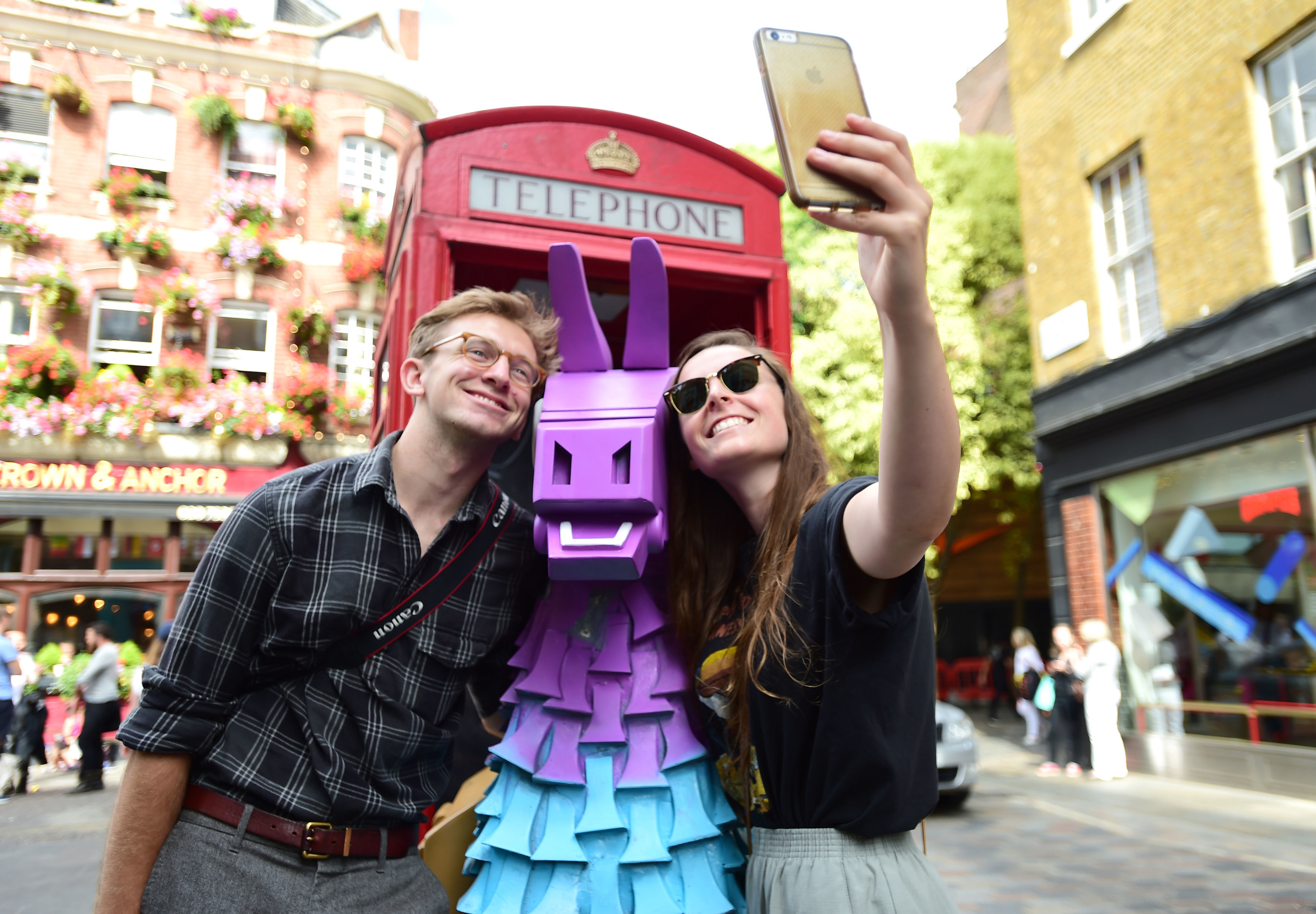 People take a selfie with a Fortnite Loot Llama in a red telephone box on Neal Street in Covent Garden, London