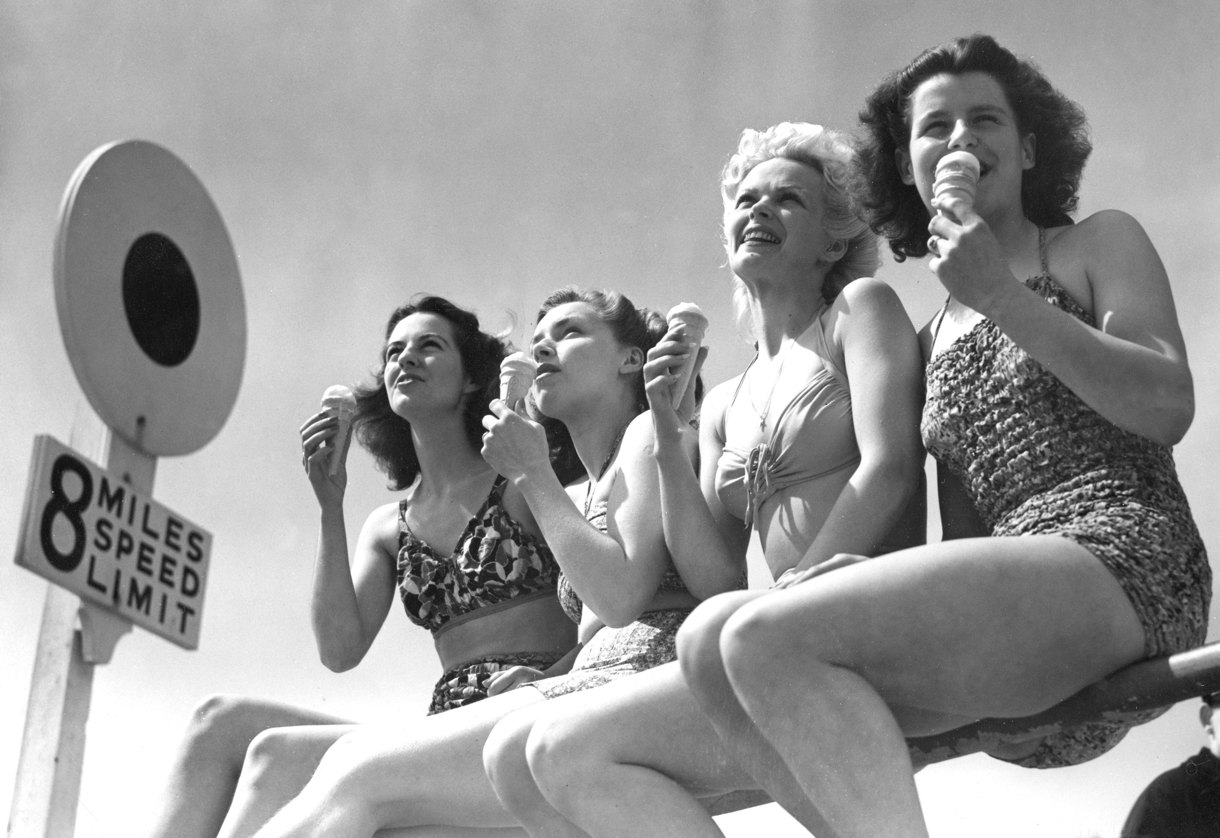 Four Whitsun holidaymakers bunched on the rails on Bournemouth front make a happy picture as they toast the sun with ice cream in 1947 (PA Archive)