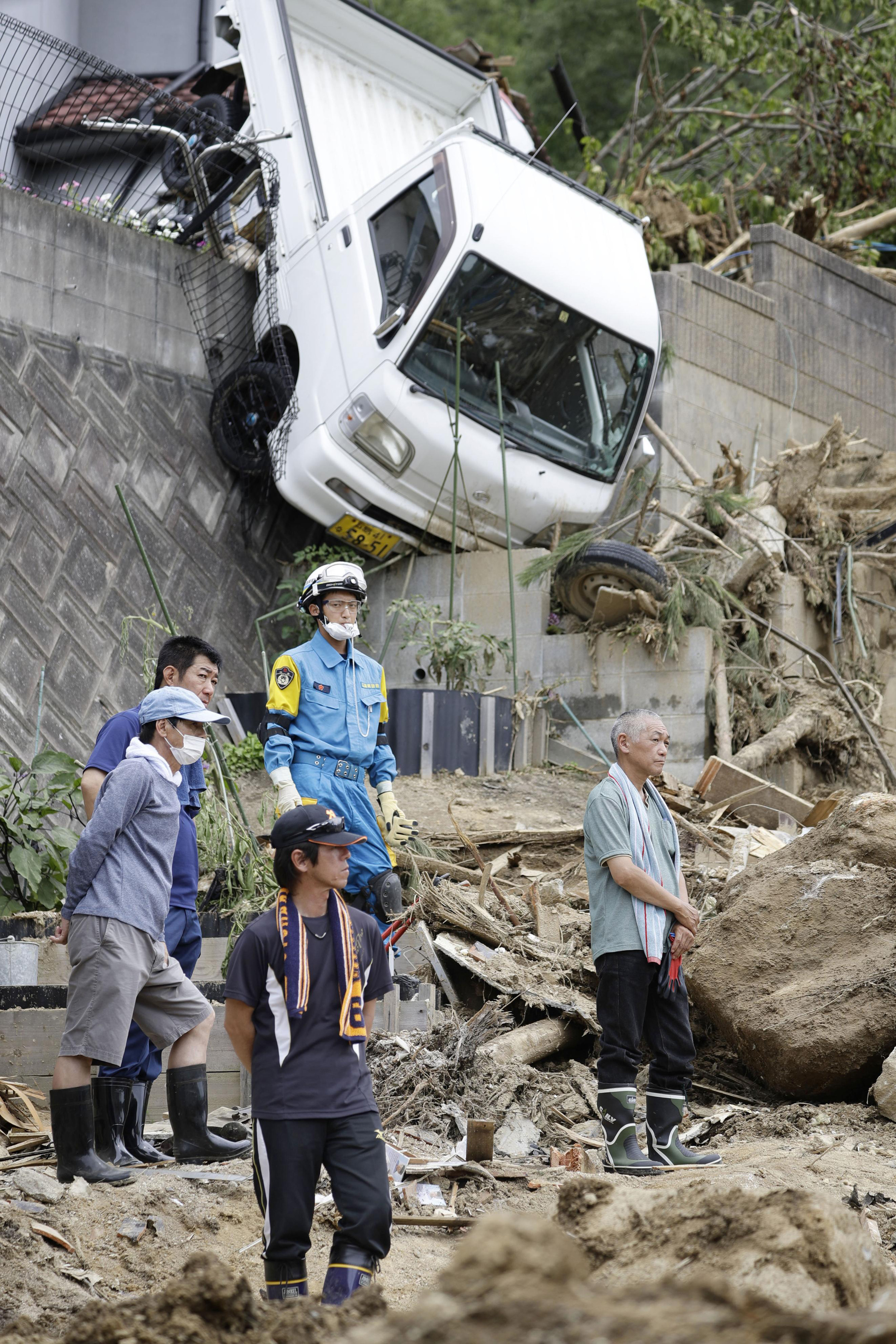 Family members watch a search operation at the site of a landslide in Kumano town, Hiroshima prefecture