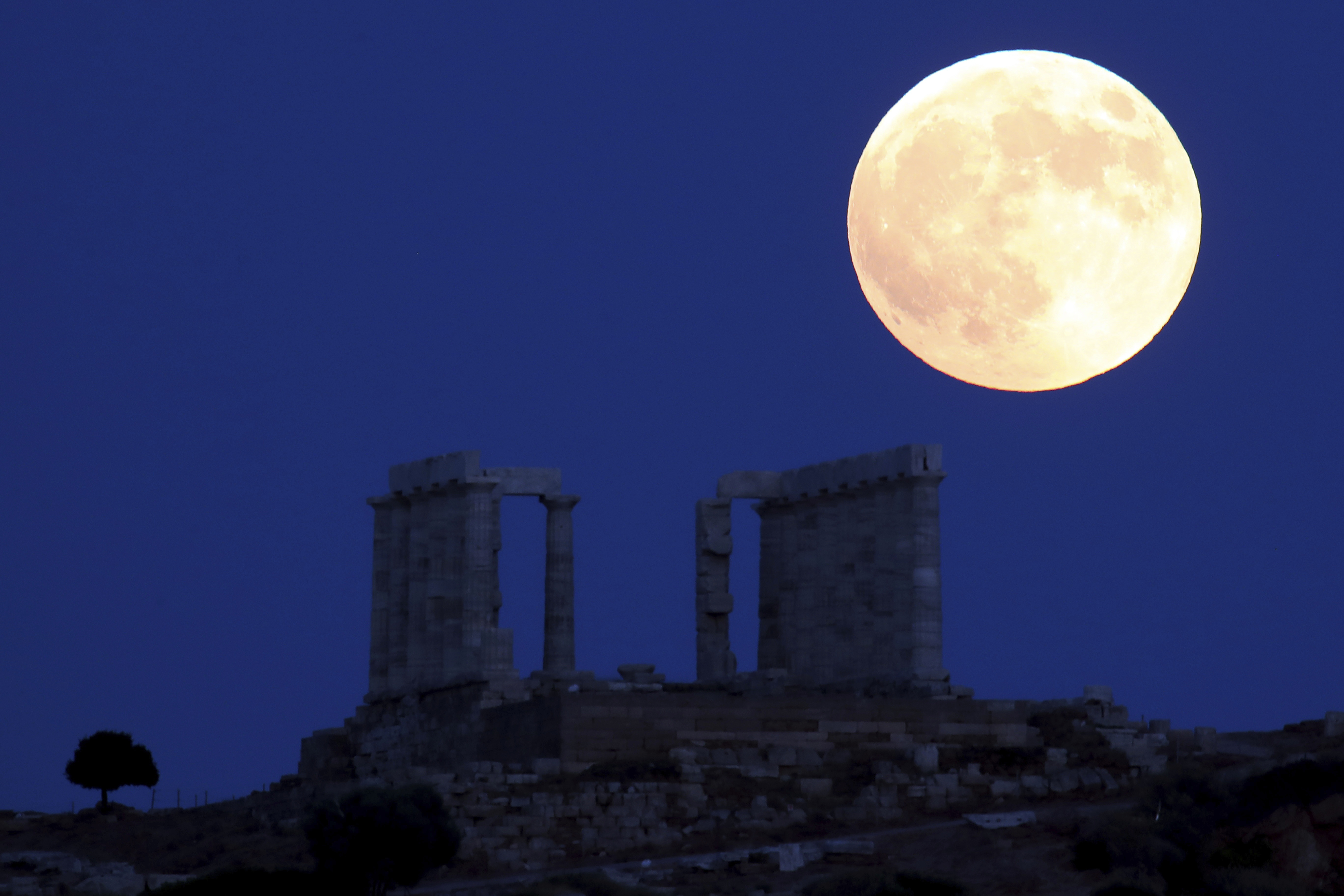 A full moon rises over the ancient Temple of Poseidon in Greece