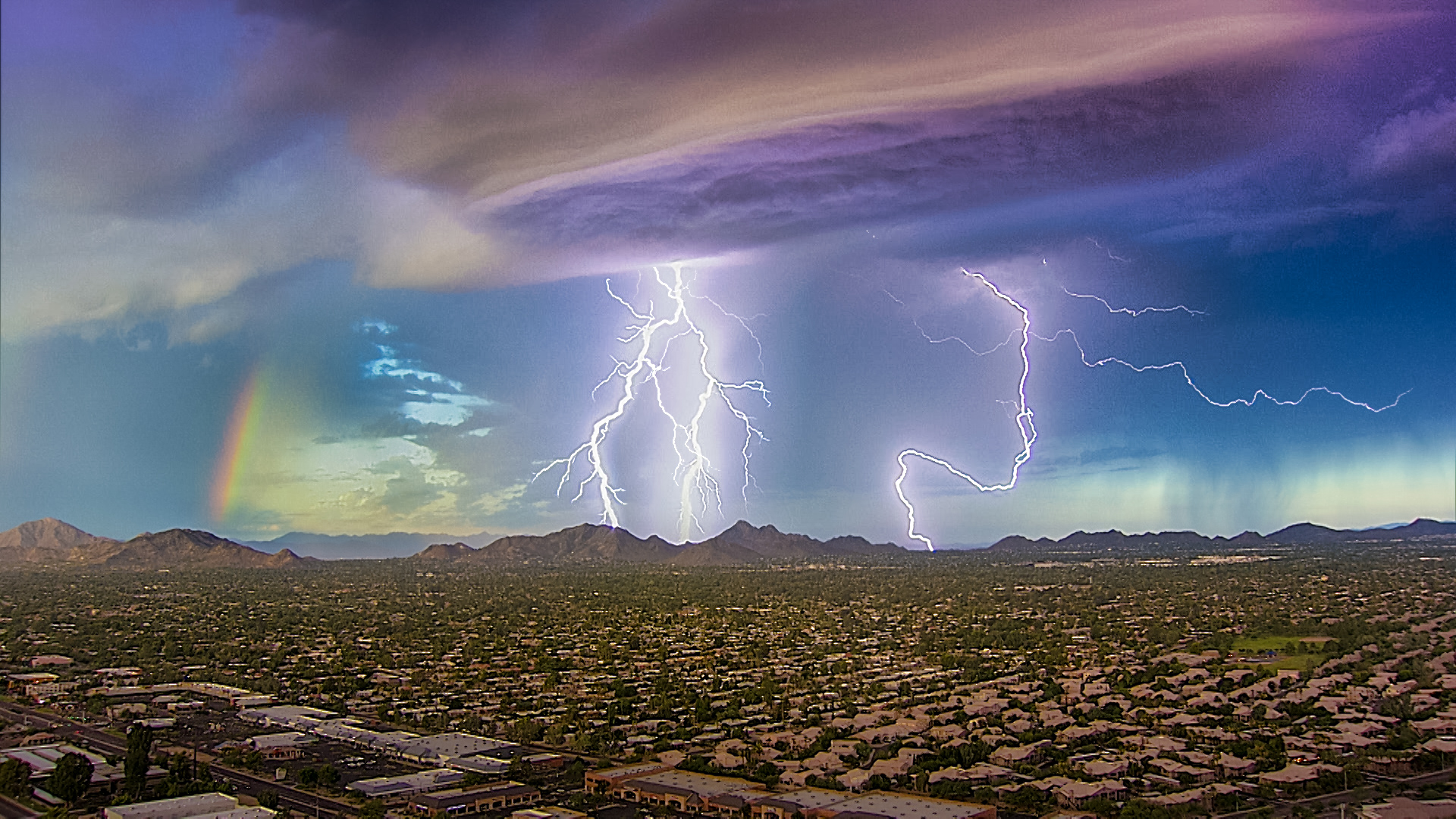 Lightning storm in Arizona with a rainbow nearby