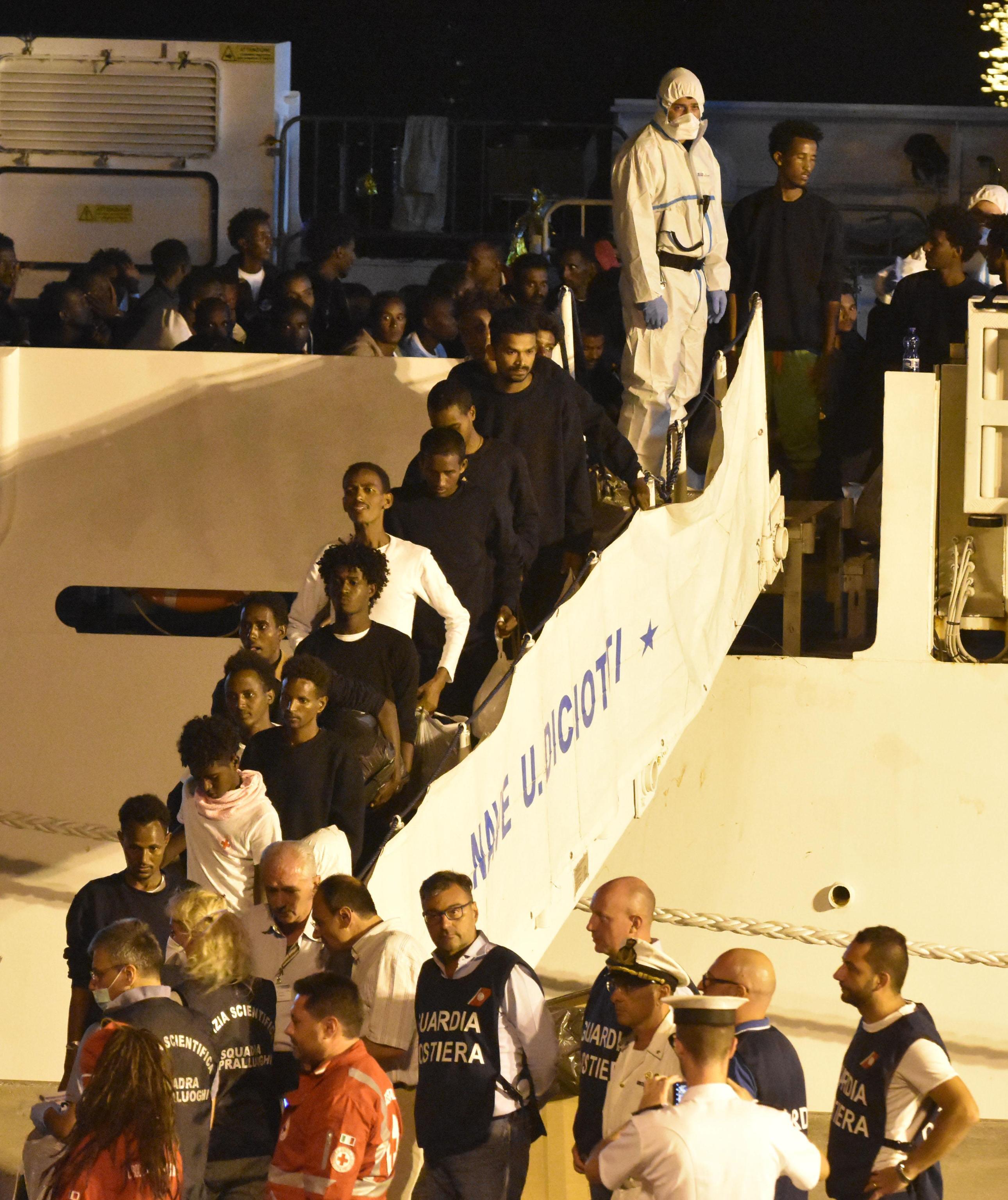 Migrants disembark from the ship