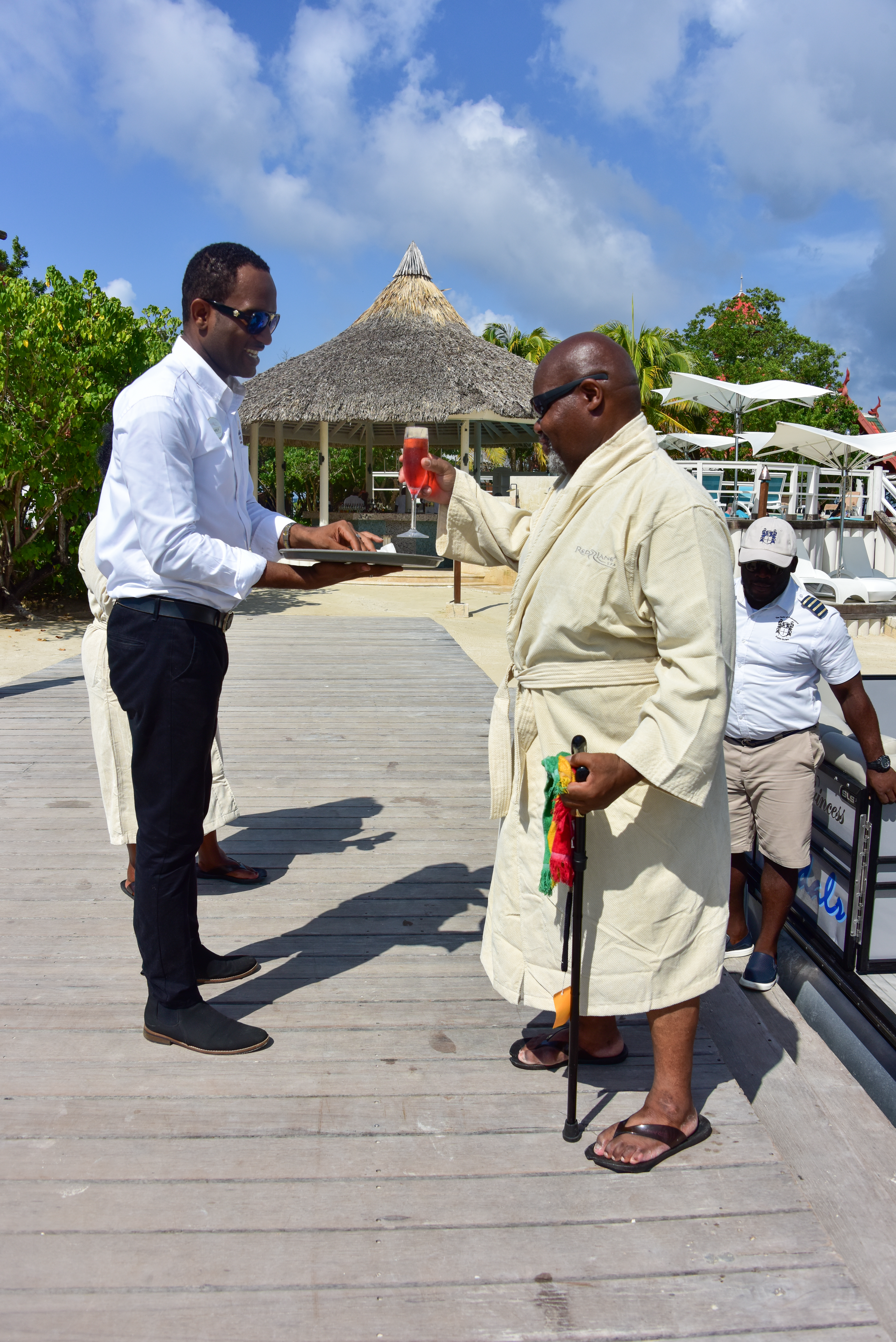 Herman Gordon accepts a drink from a waiter at Sandals Resorts in Jamaica after students at the University of Bristol crowdfunded the money for their flights