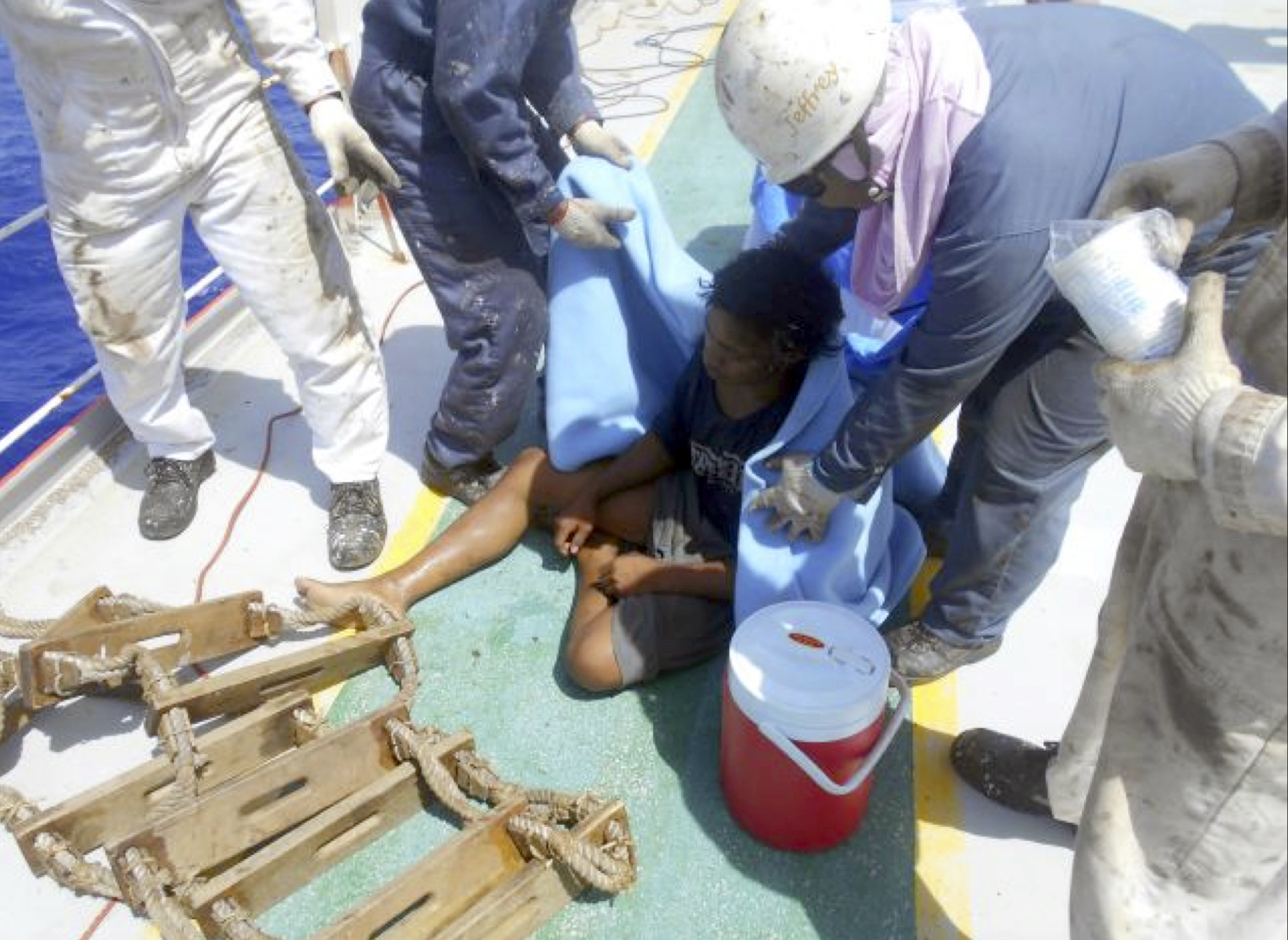 Aldi Novel Adilang sits on the deck of the MV Arpeggio after being rescued