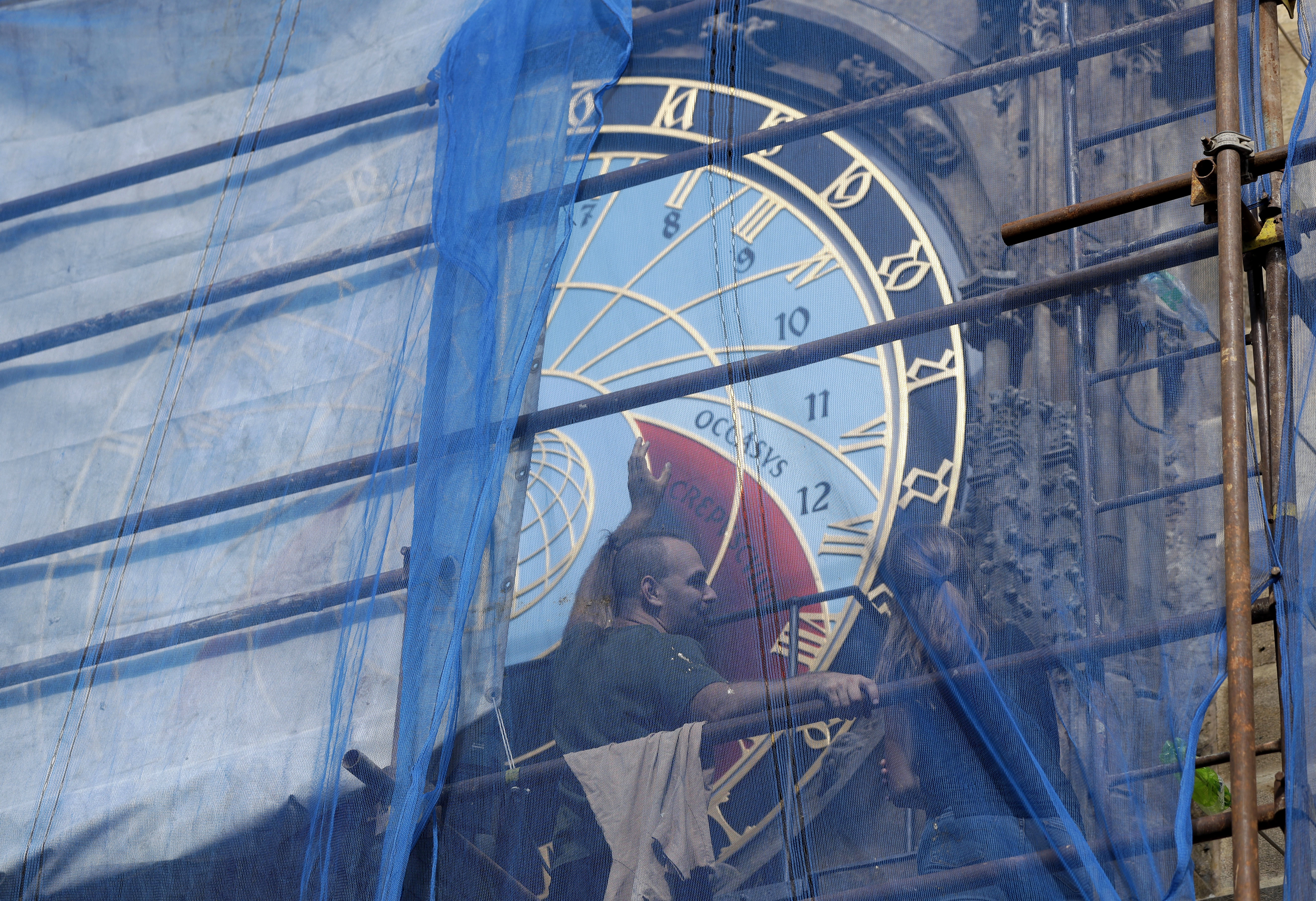Workers adjust the newly restored parts of the famed Prague's medieval astronomical clock