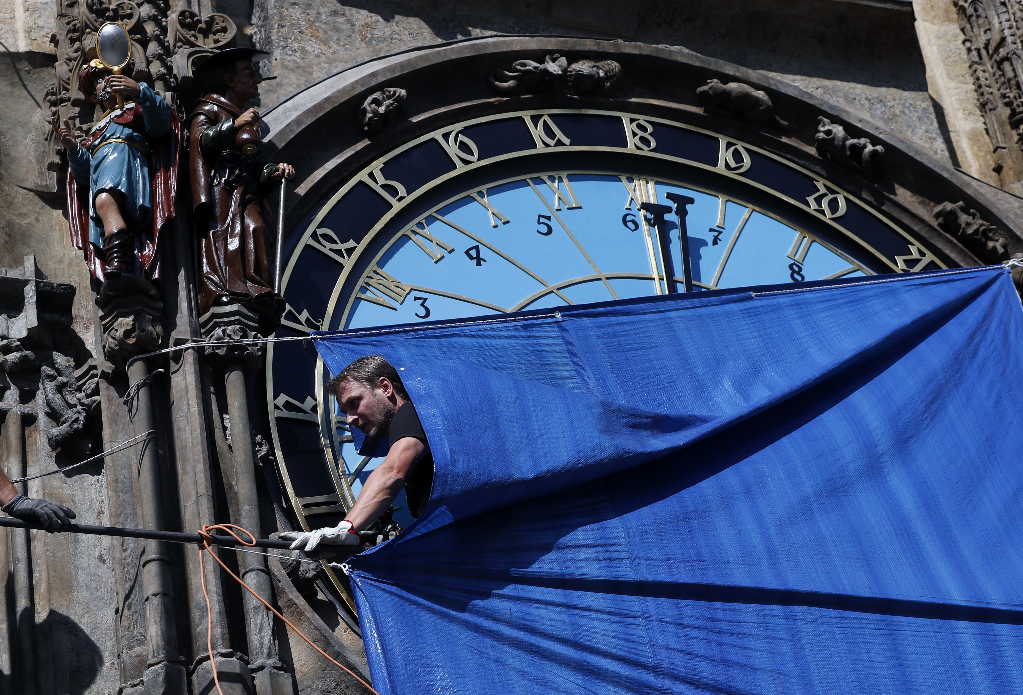 A worker walks under a cover at the famed Prague's medieval astronomical clock