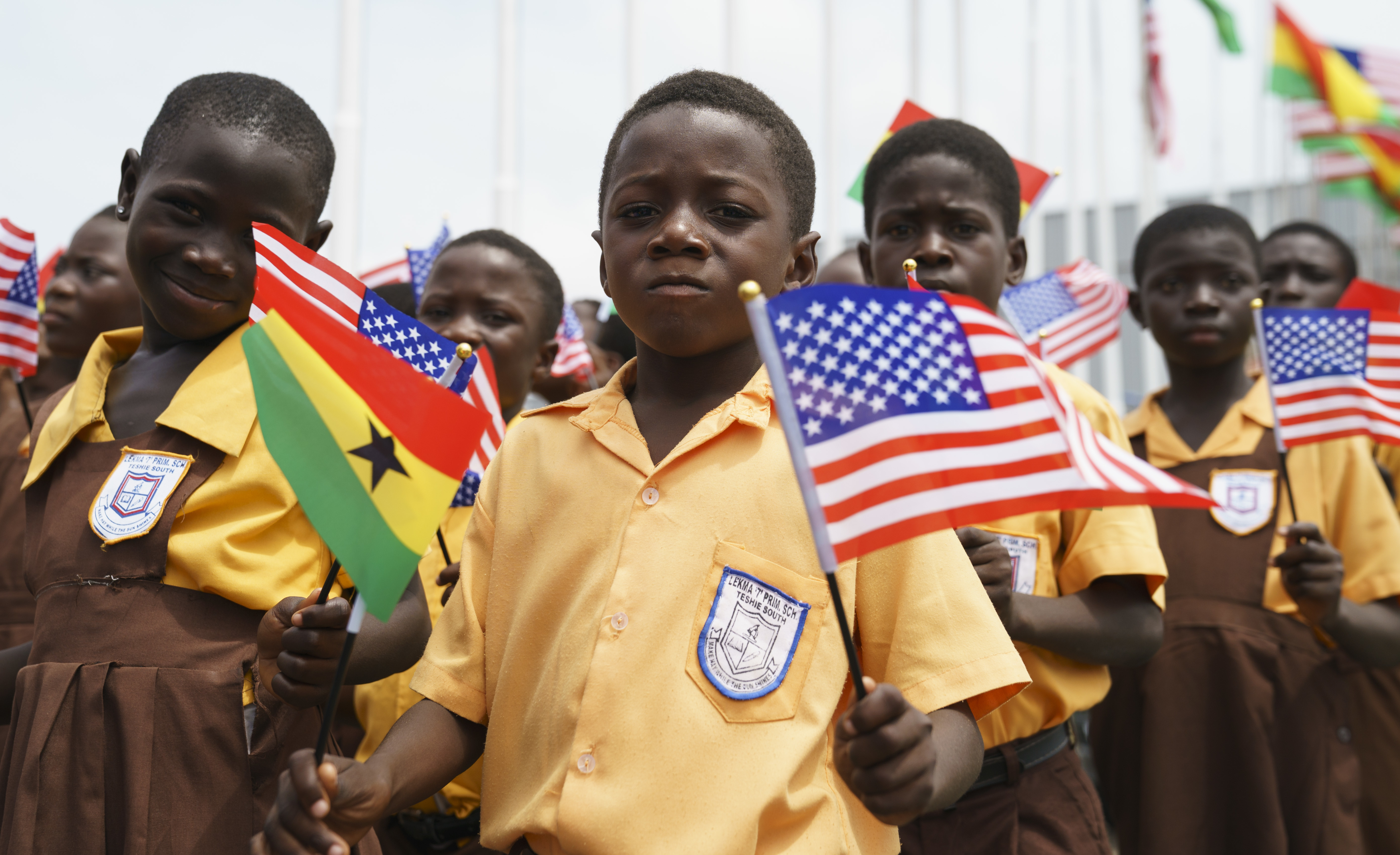 Children wave American and Ghana flags during an arrival ceremony for first lady Melania Trump 