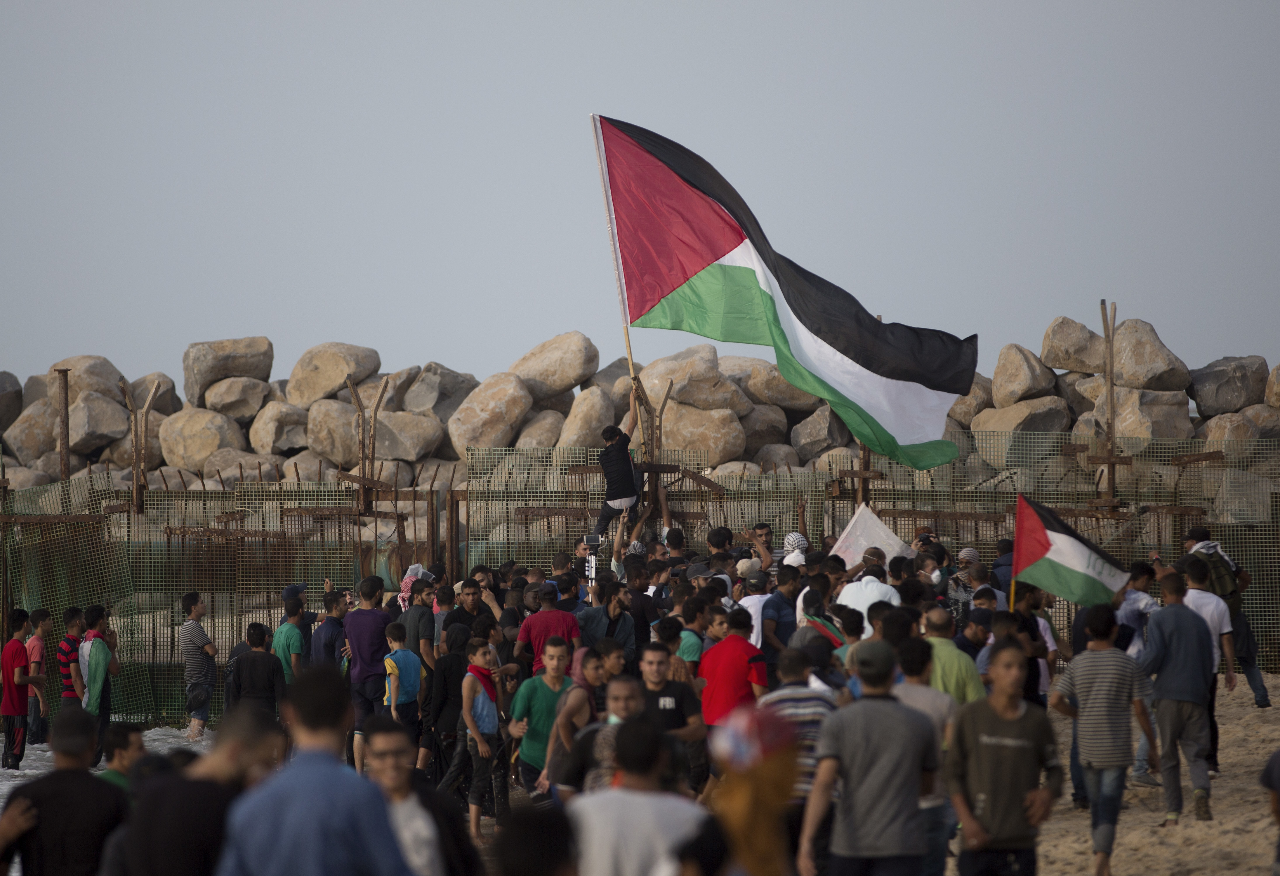 Palestinian protesters hang a national flag at the border fence