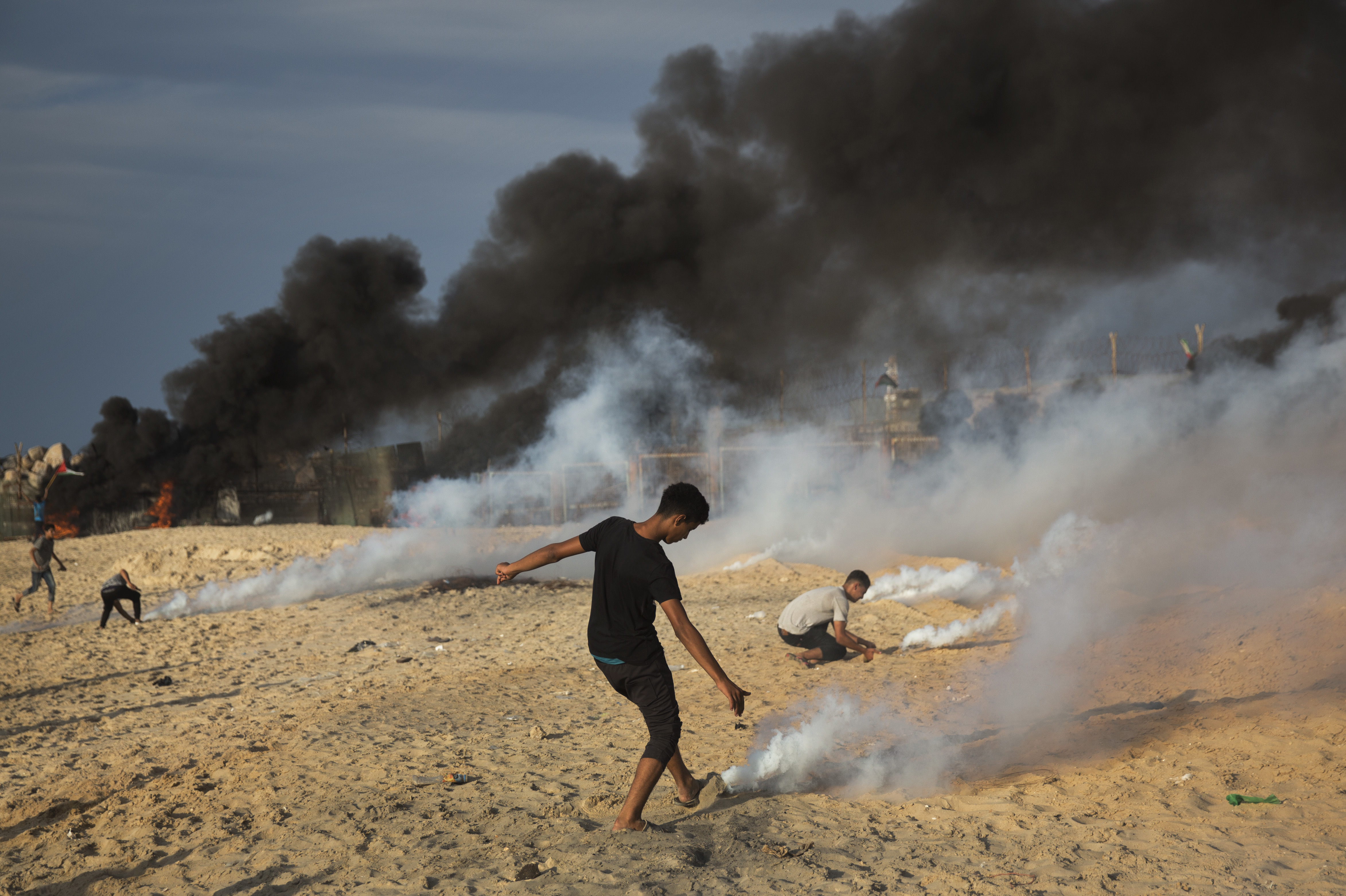 Palestinian protesters cover teargas canisters with sand 