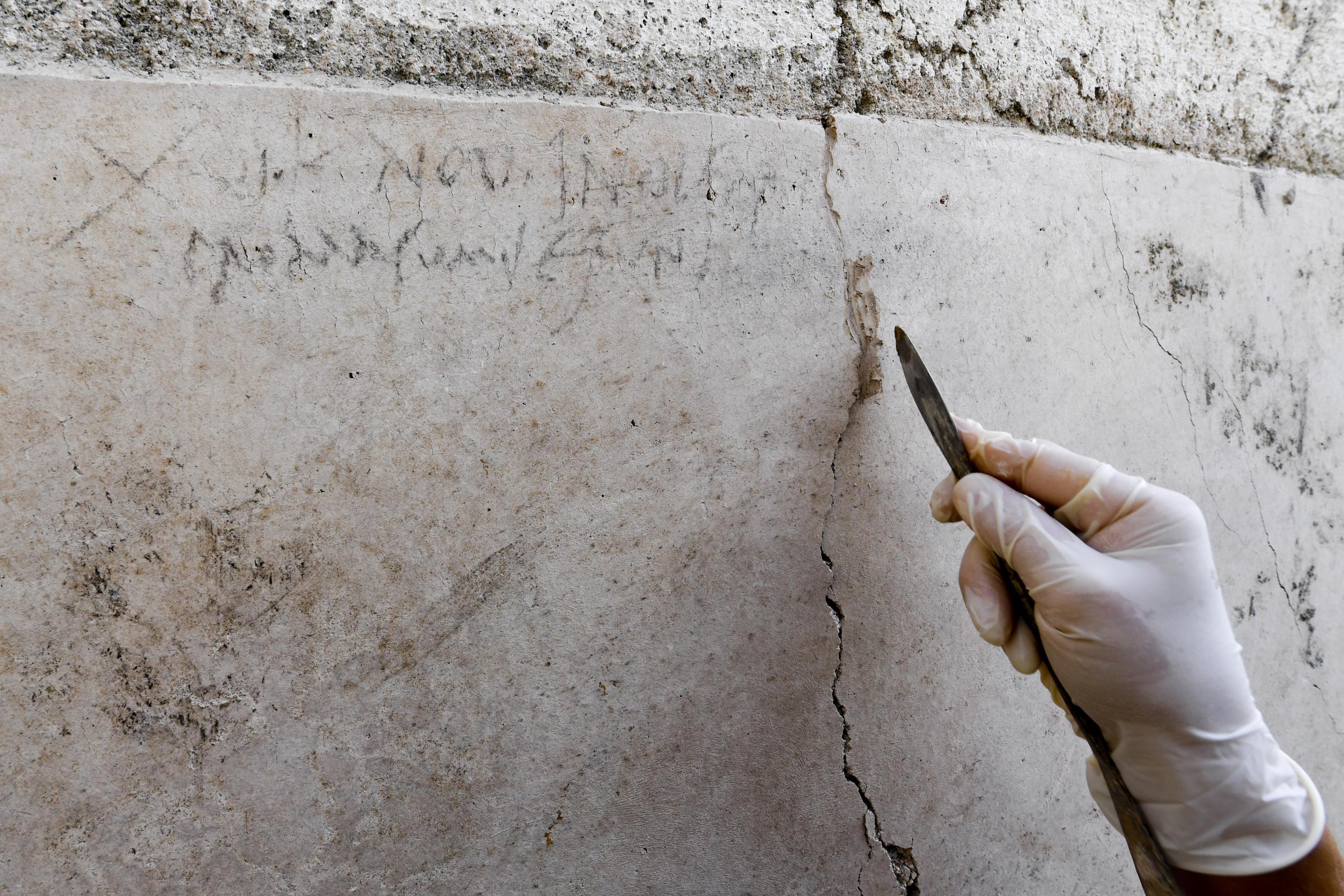 An archaeologist checks inscriptions on a wall during new excavations at the Pompeii archaeological site
