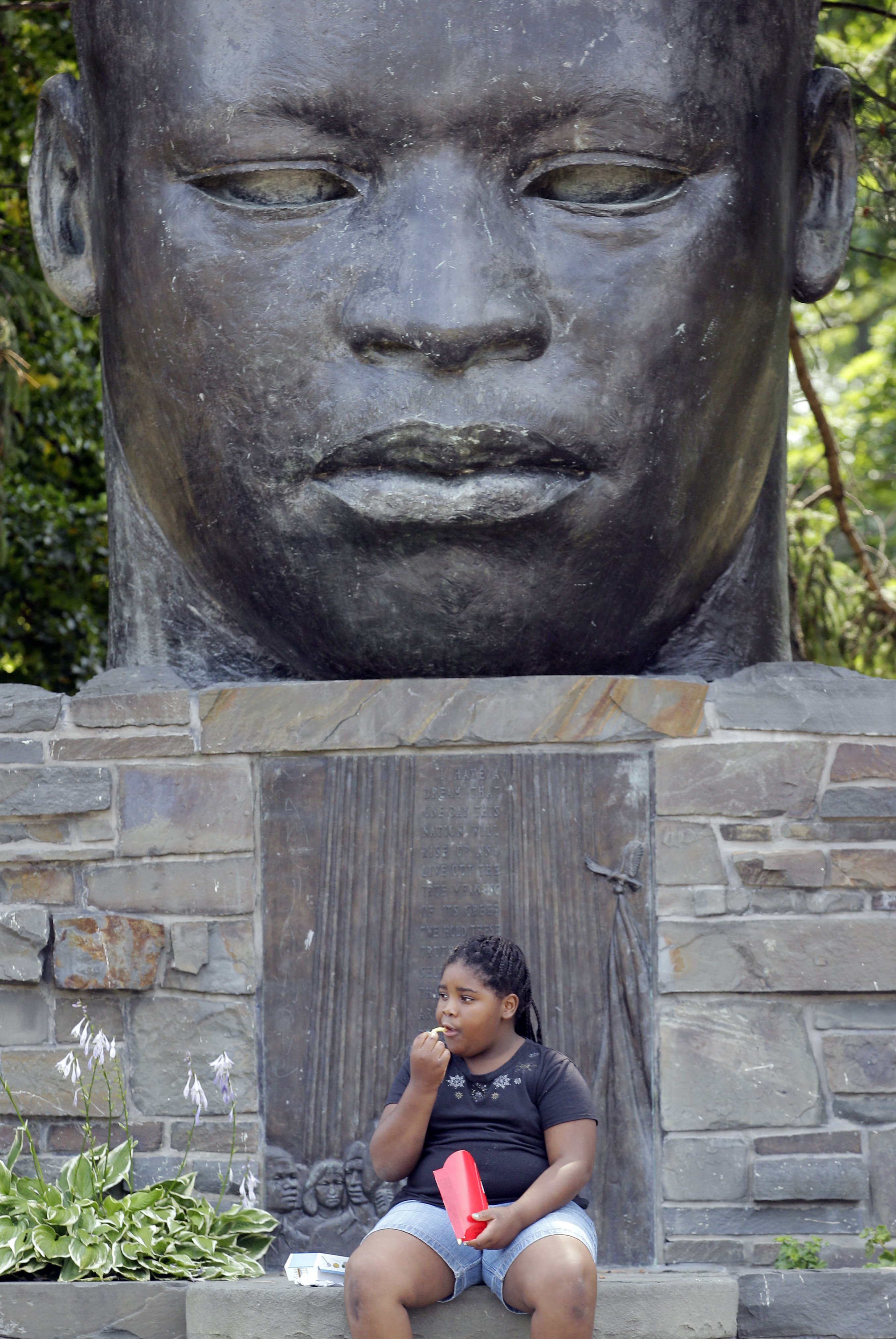 Tonae Johnson eats her lunch in the park in front of a Martin Luther King Jr statue in Buffalo