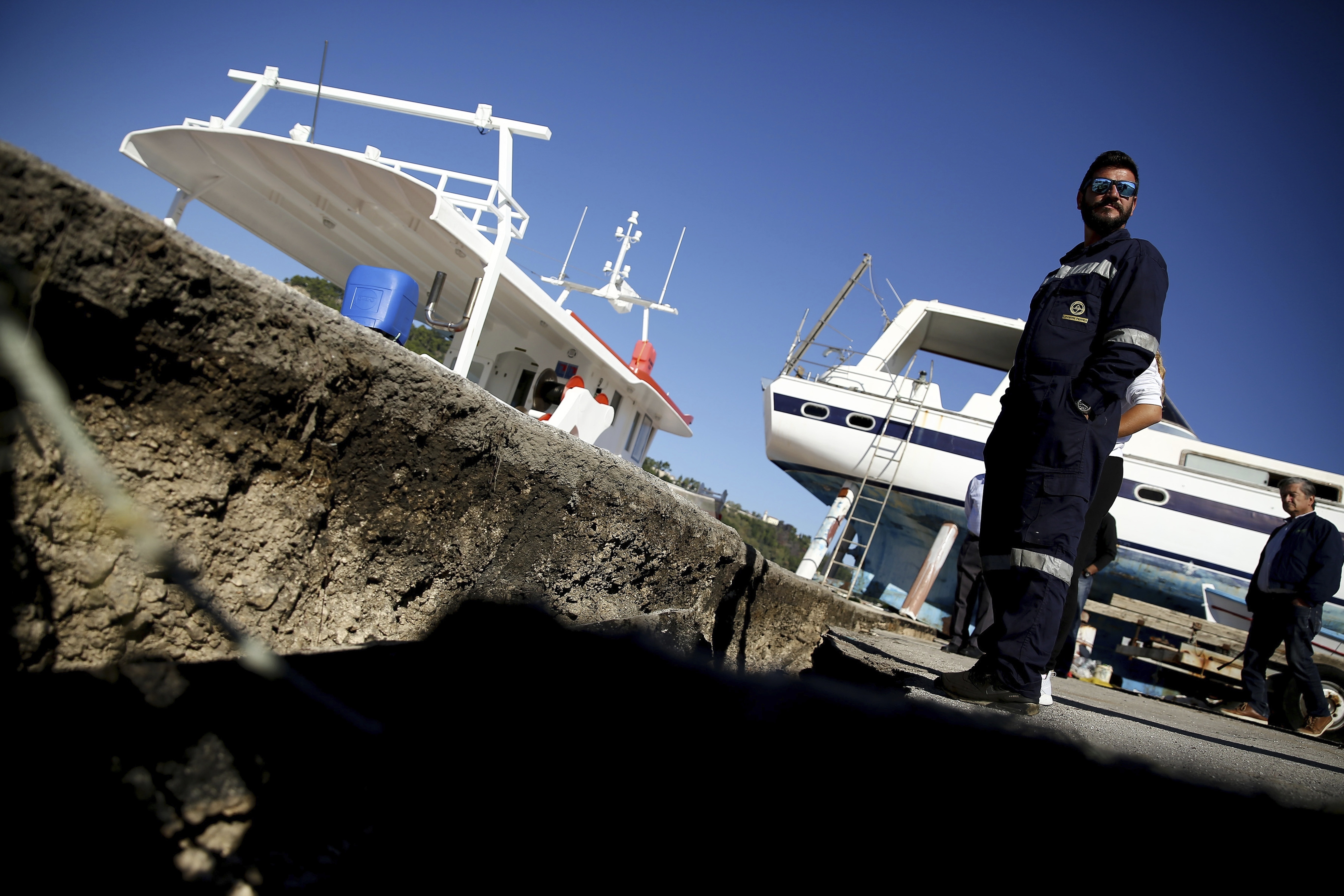 A worker stands over the cracked and warped sidewalk after an earthquake at the main harbor of Zakynthos island